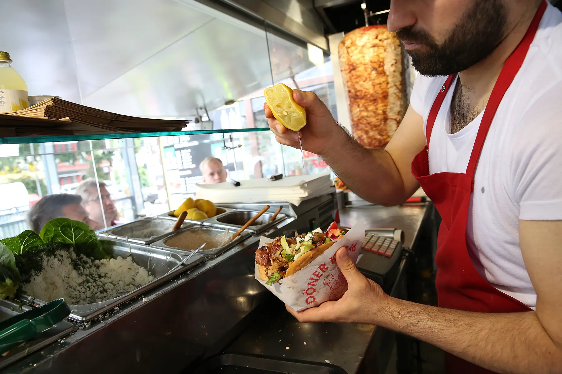 Employee adding lemon to a döner kebab in his food truck