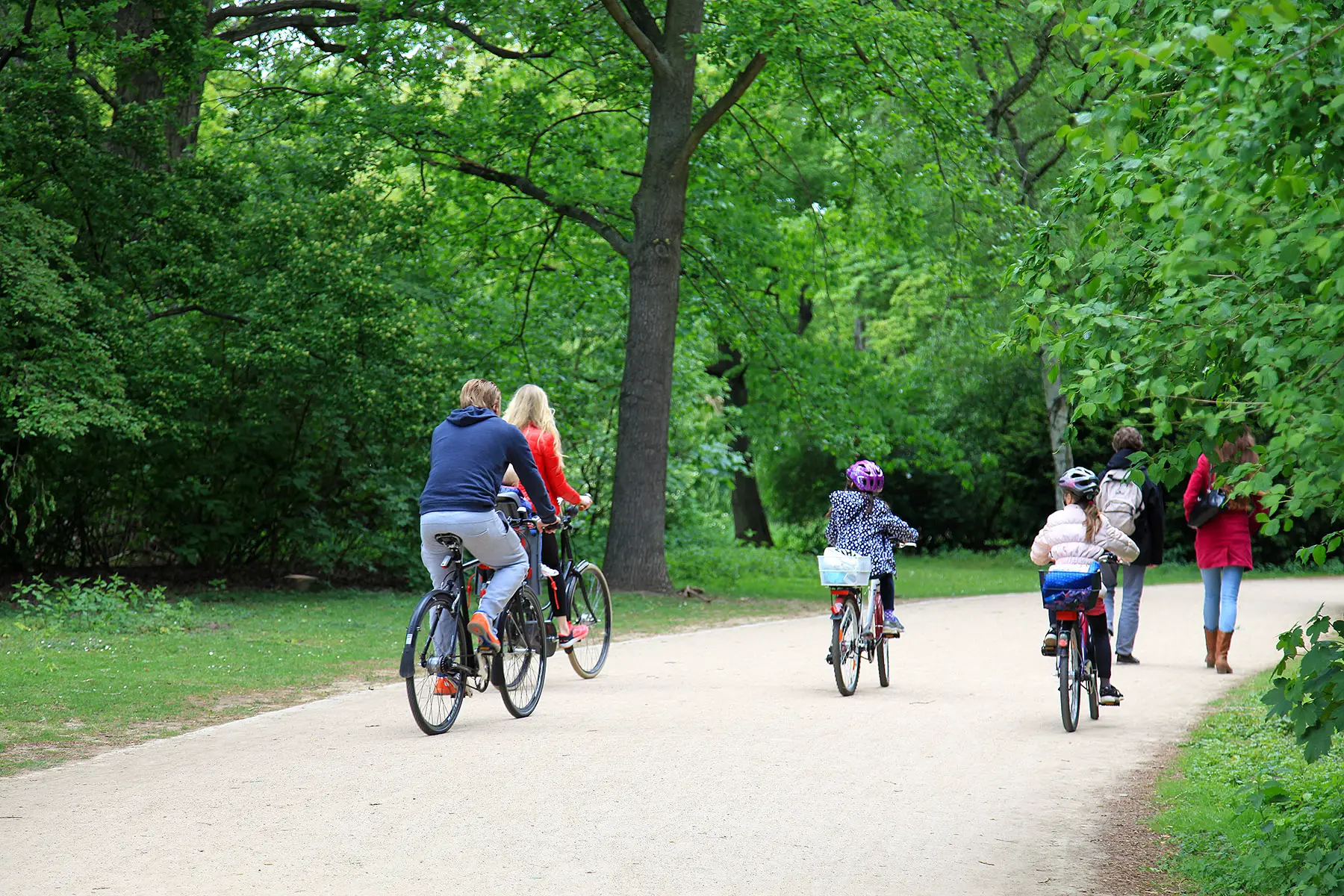 Family cycling through a park in Berlin
