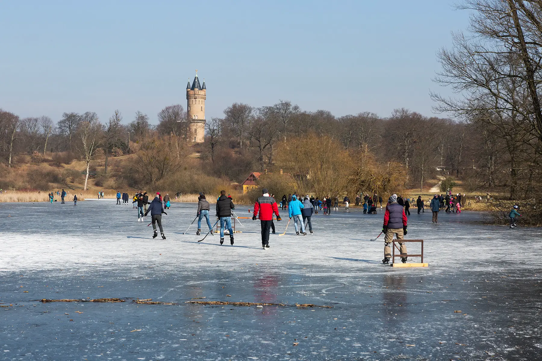 Friends playing ice hockey outside on a frozen lake in Potsdam