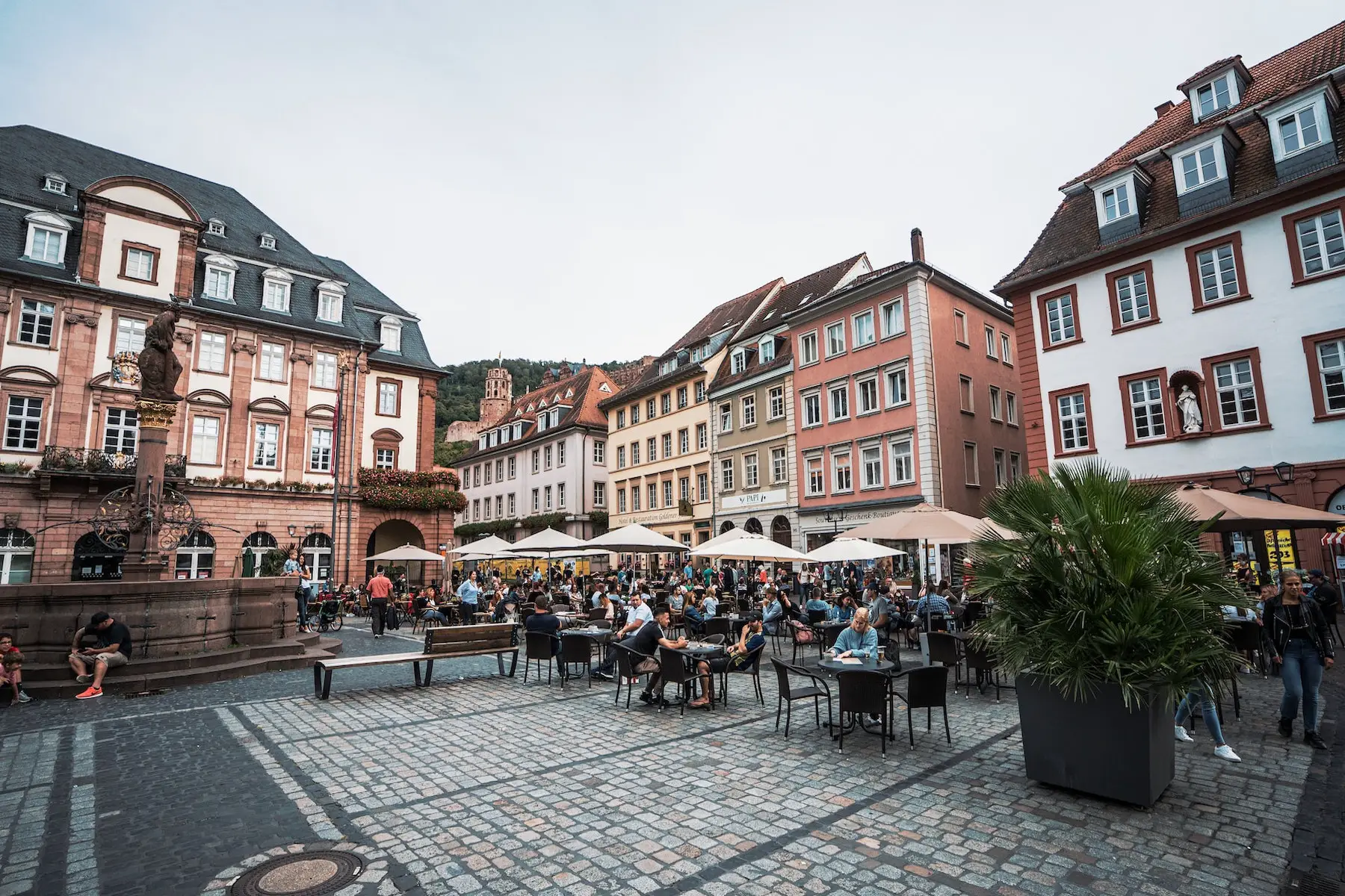 An old German market square is lined with restaurants and umbrella-covered tables