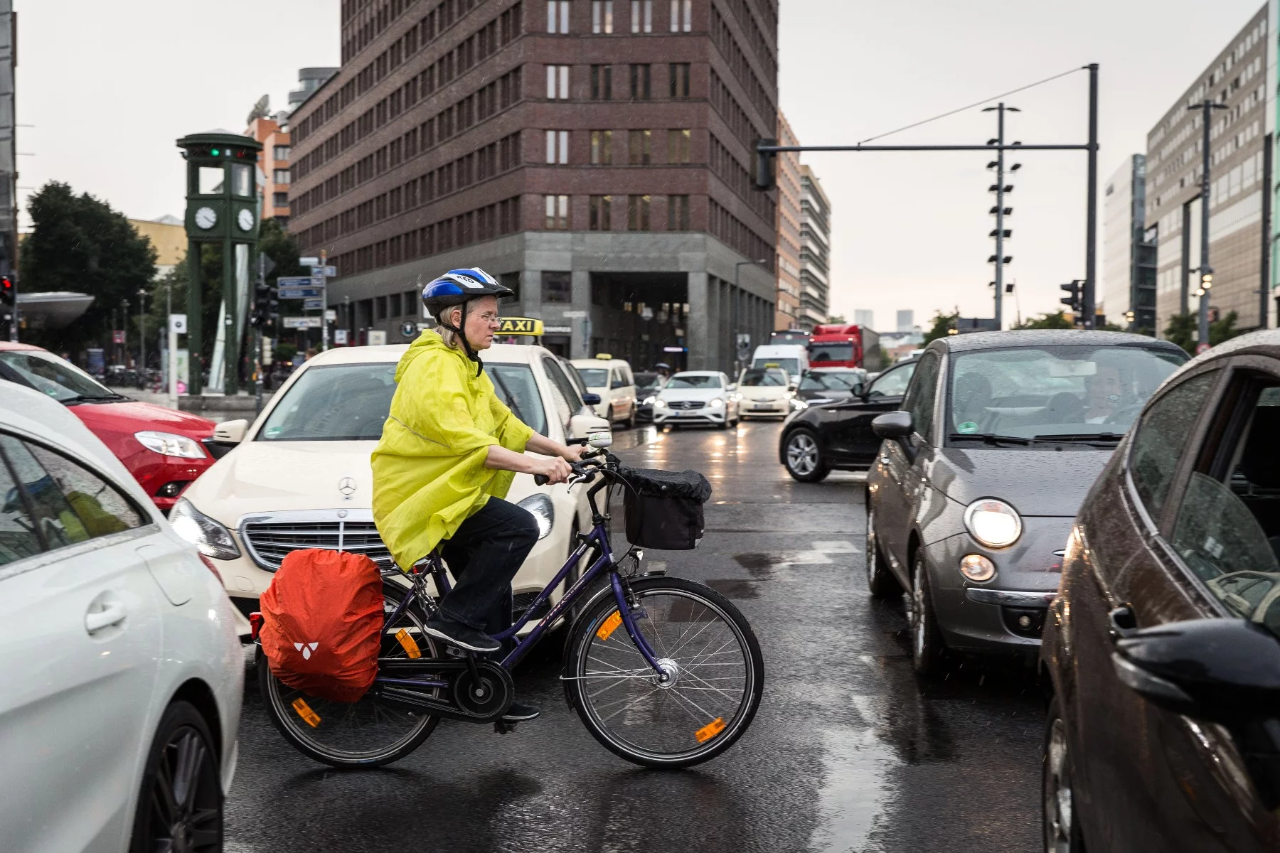 Woman wearing a helmet and cycling through heavy traffic at Potsdamer Platz, Berlin, Germany.