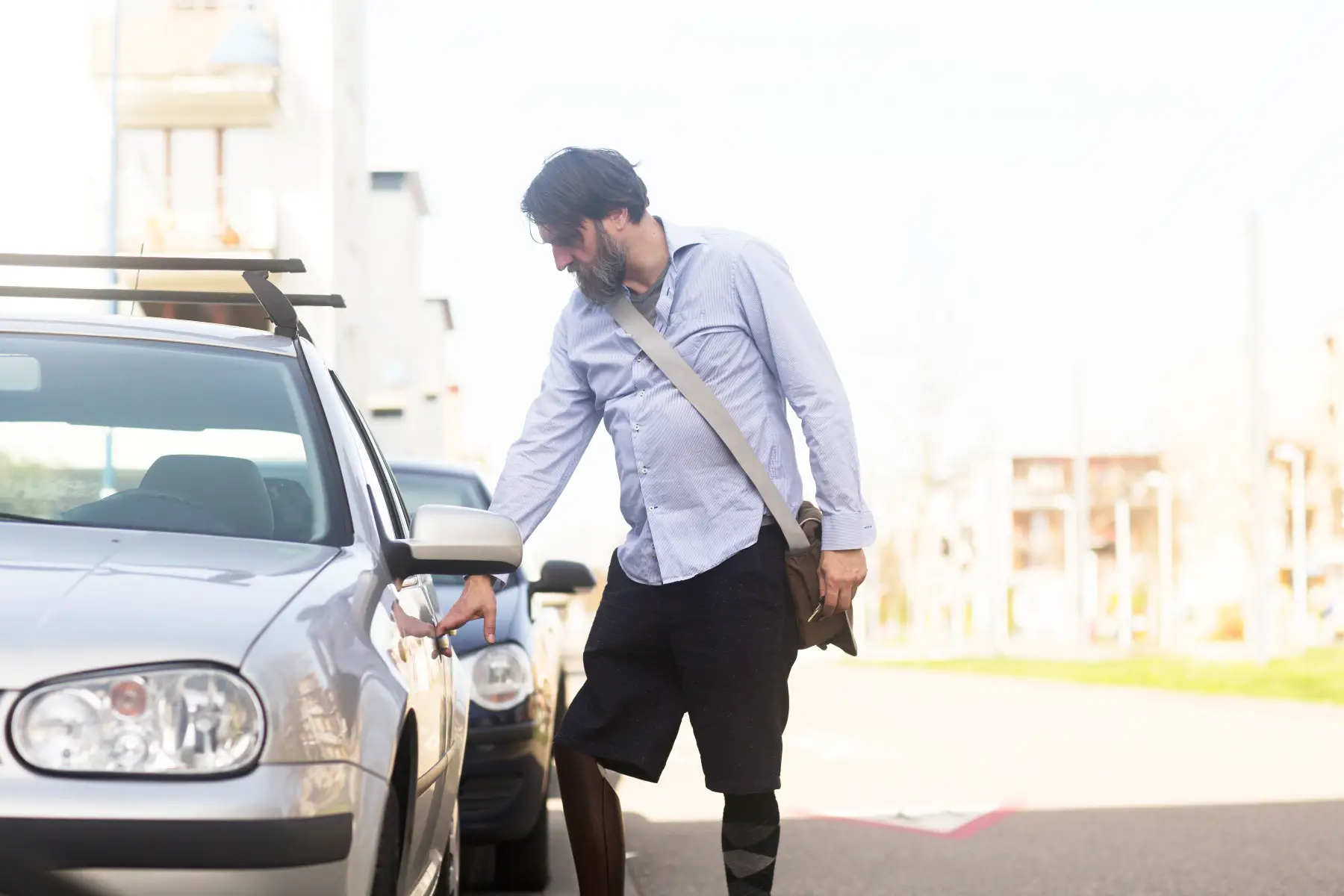 Man with a prosthetic leg ready to open his car.