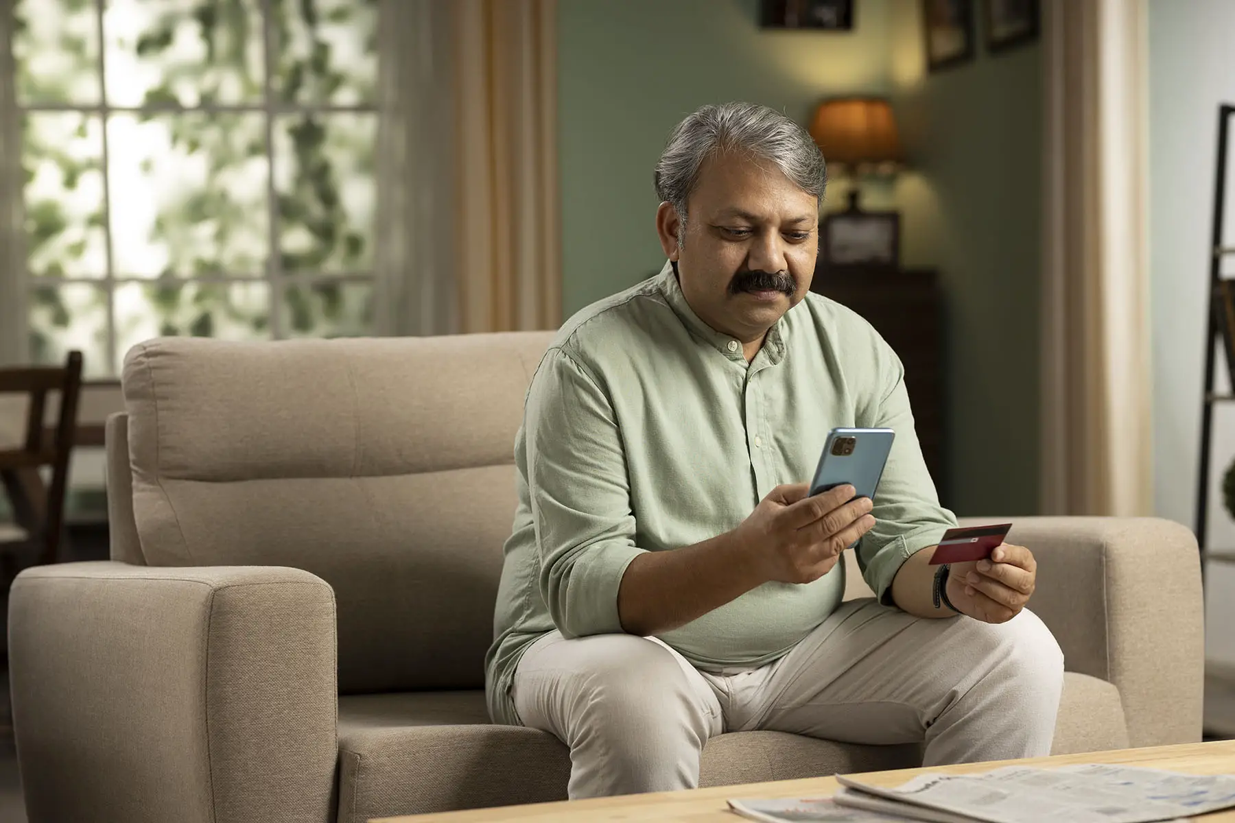 Man checking his bank saldo on his phone while sitting on the couch.