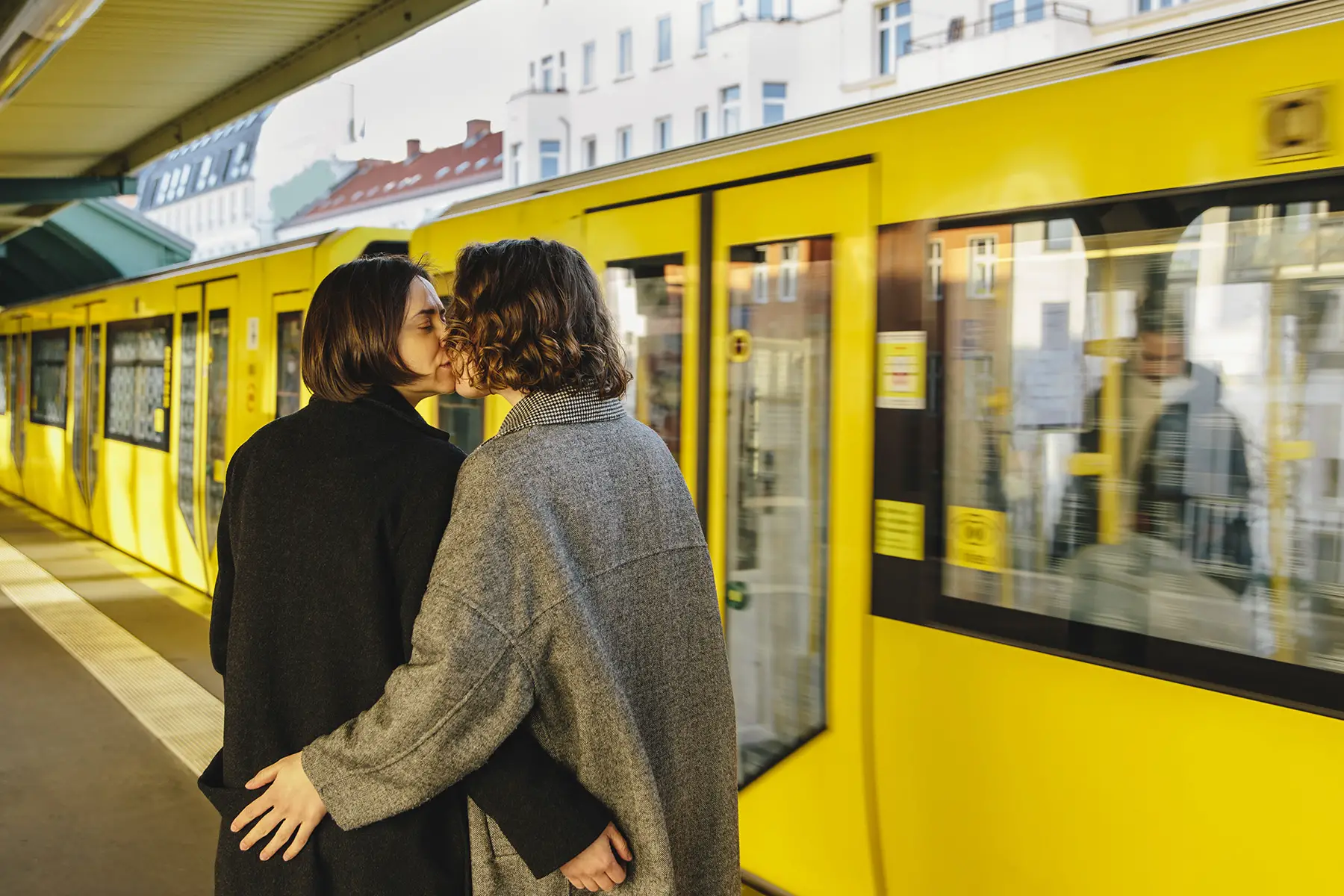 A lesbian couple kissing in front of a train