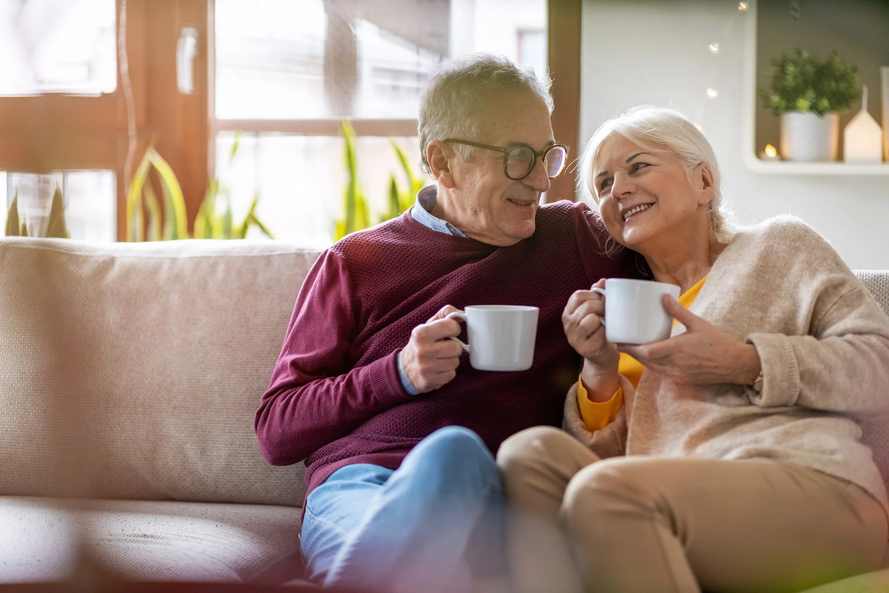 retirees sat on a sofa drinking from mugs