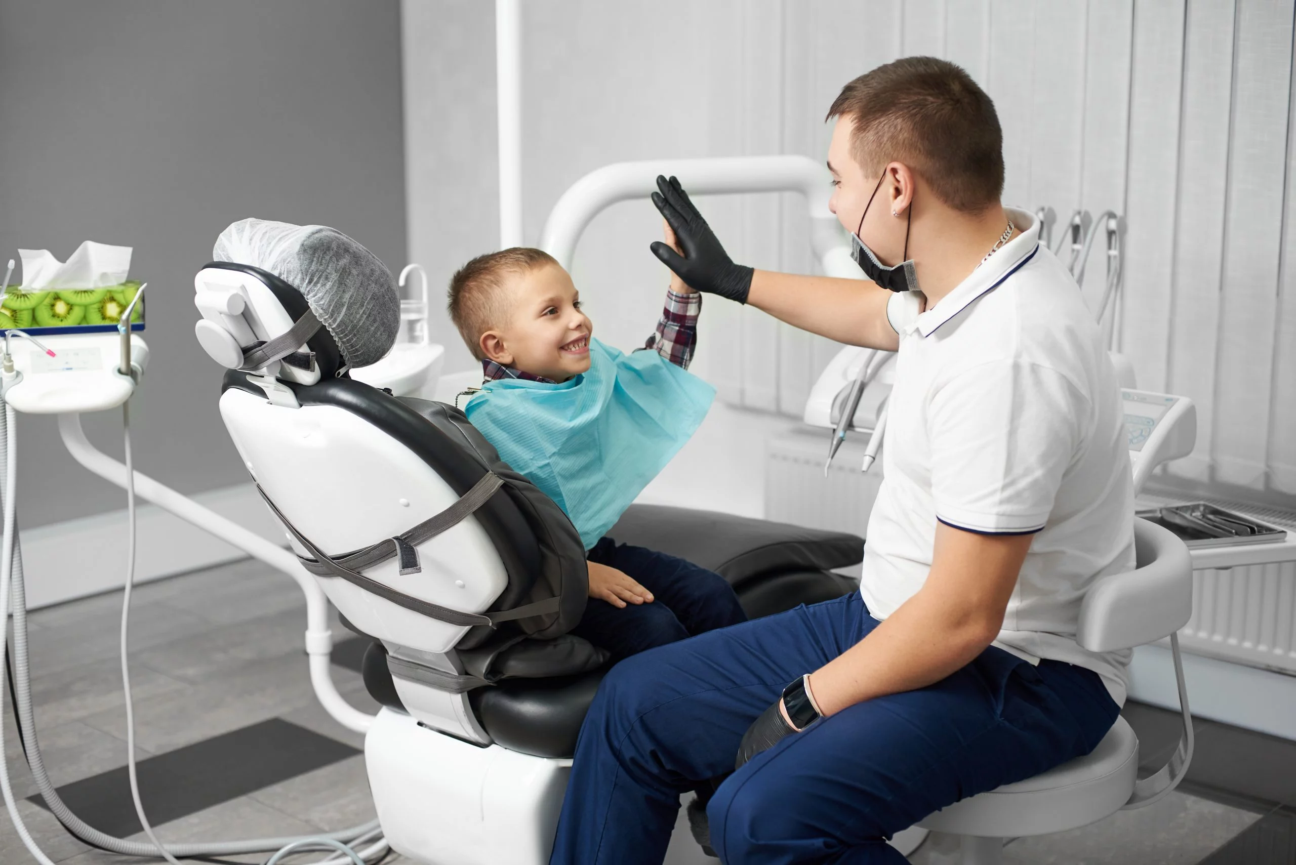 dentist and young boy high fiving in dental clinic