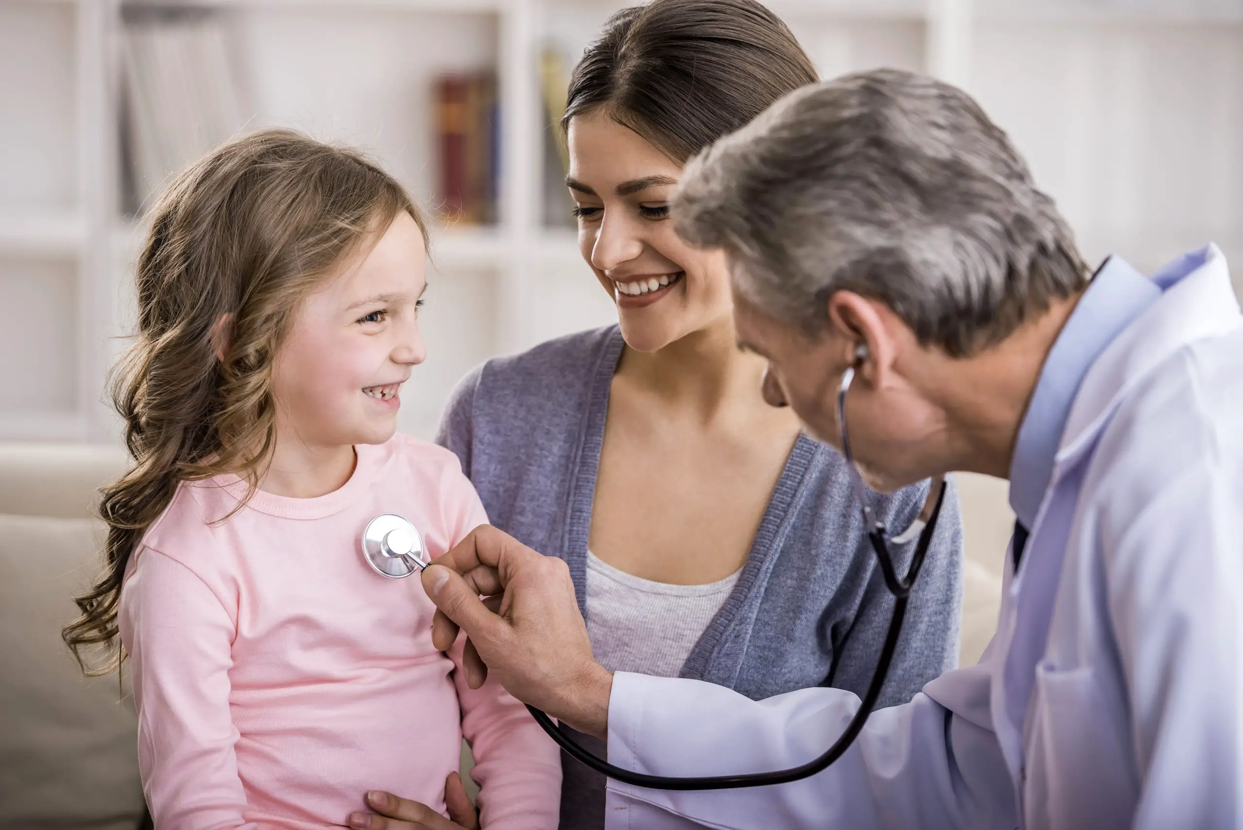 children's healthcare professional checks the heartbeat of smiling young girl in Germany