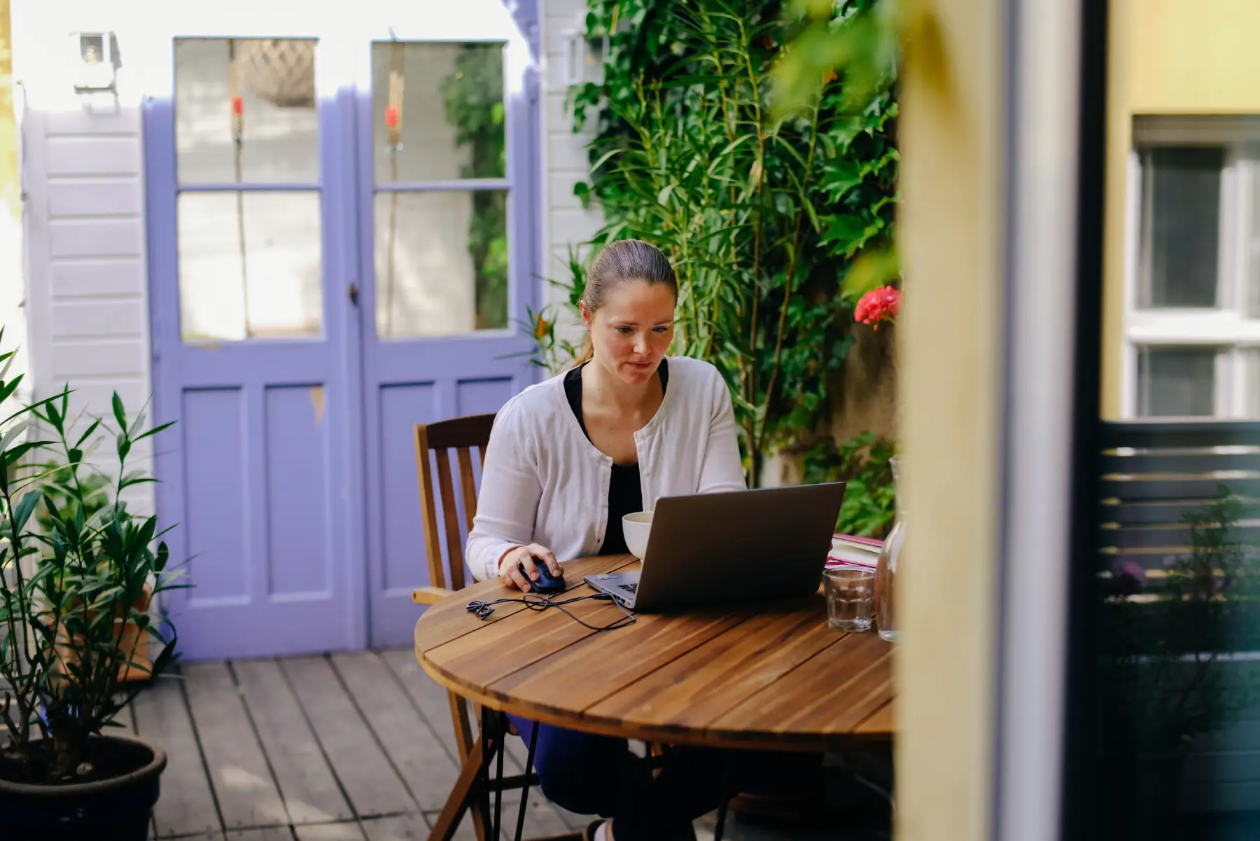 Woman using laptop from home garden in Berlin