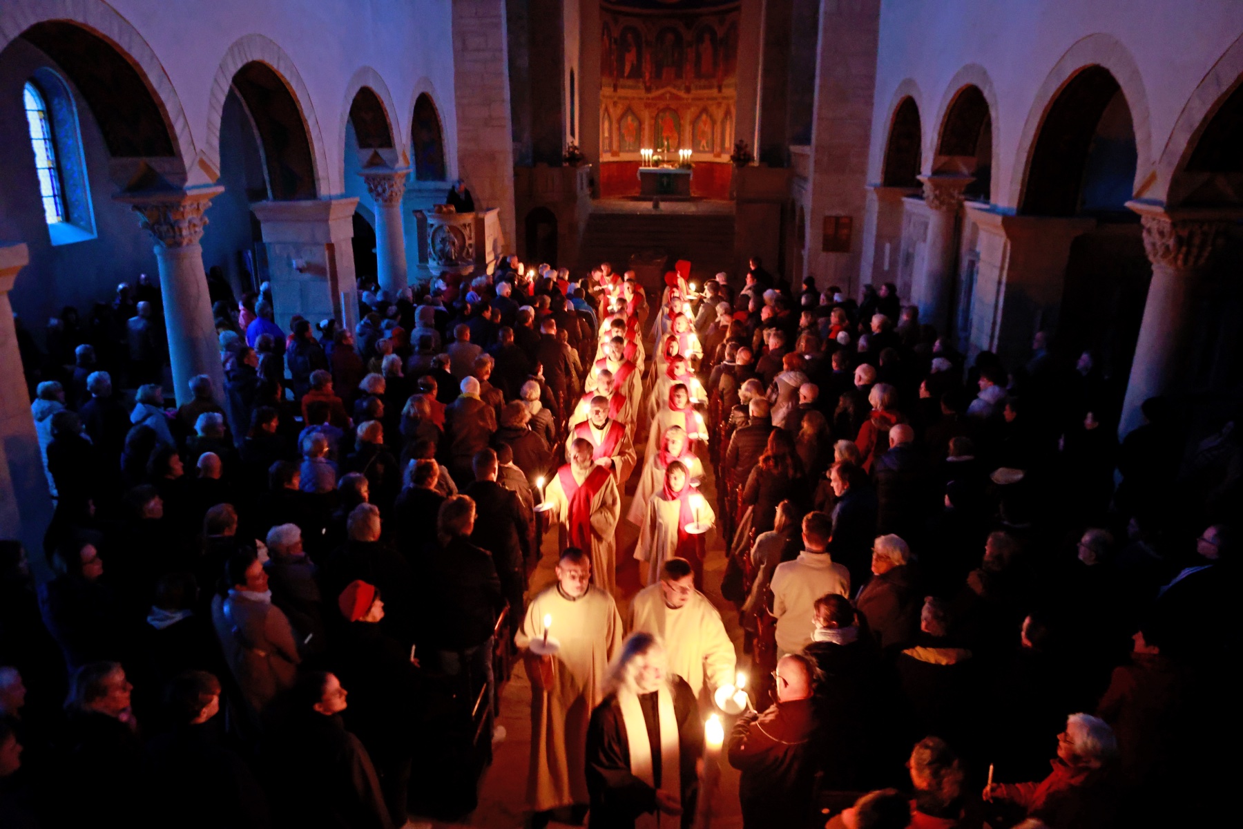 Easter Sunday mass celebrations, with priests in a row holding candles in a darkened church