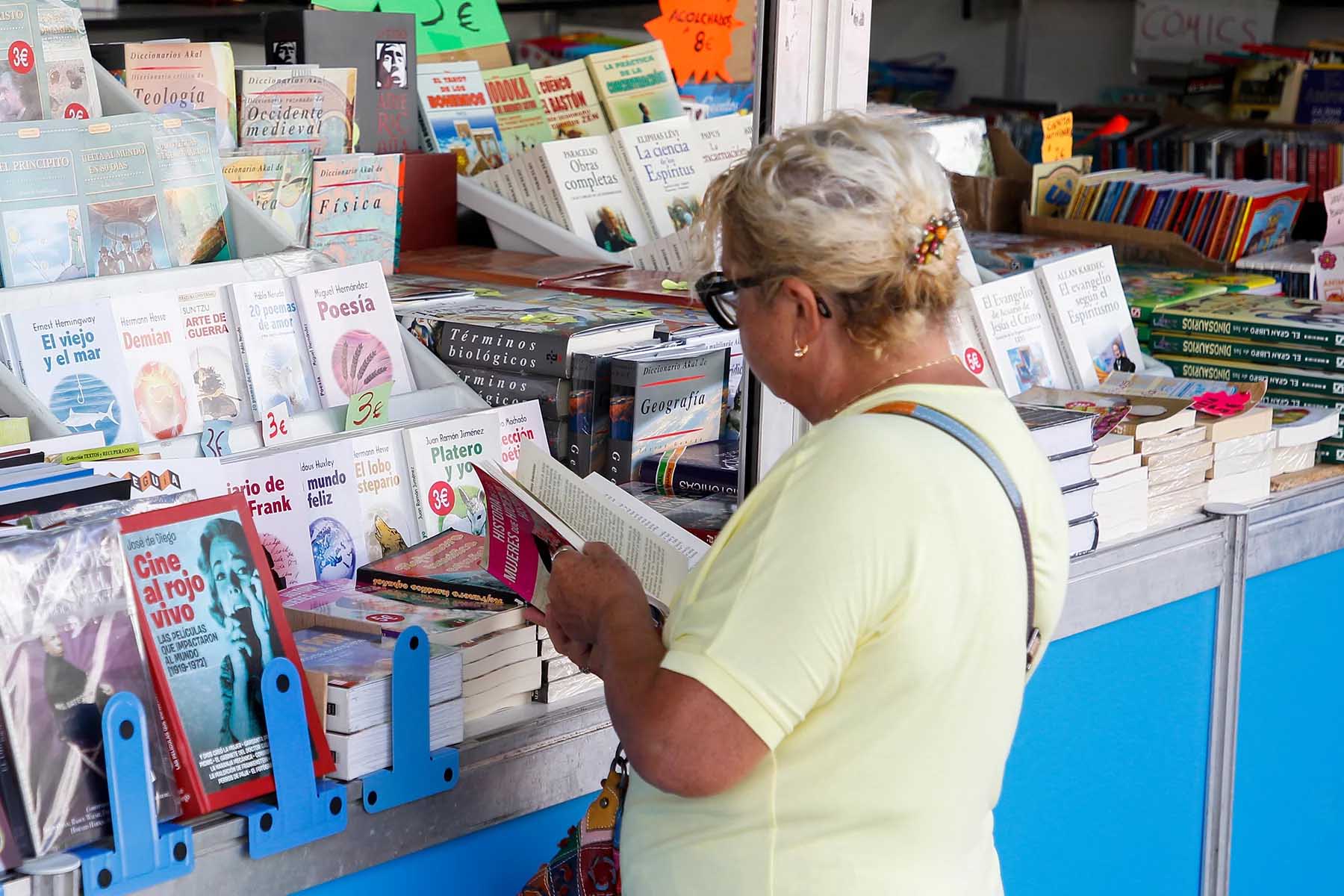 Lady browsing a Spanish language book at a stand.