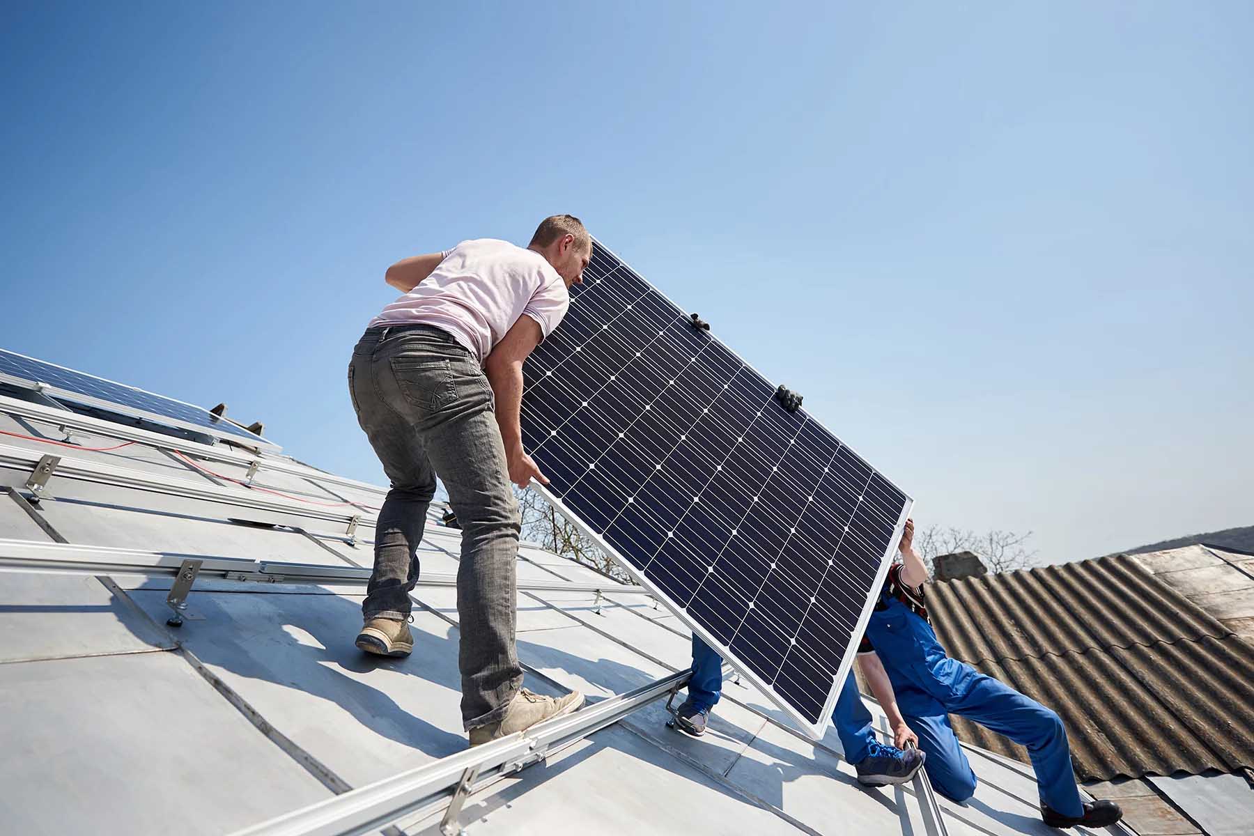 Three professionals installing solar panels on the roof of a home in Spain.
