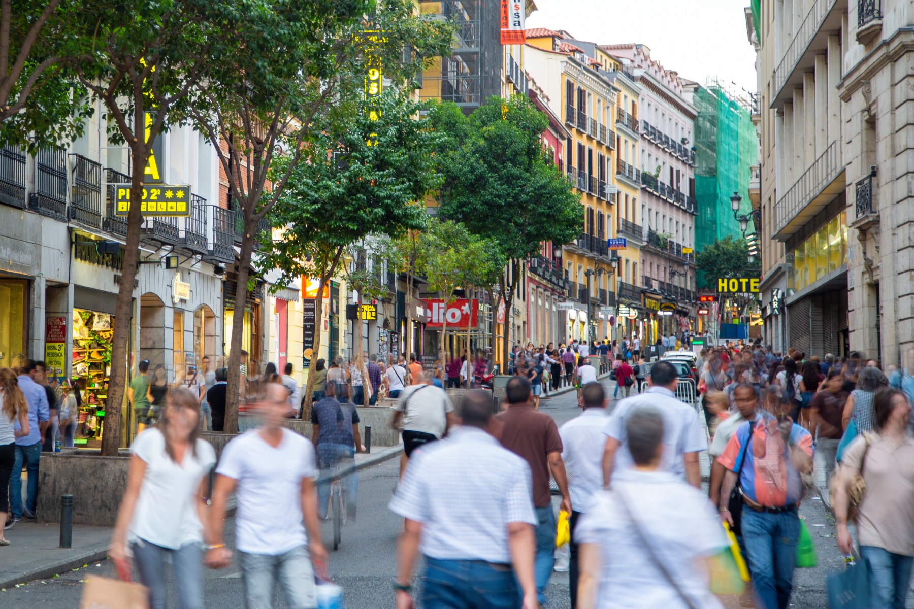 a blurred image of people walking along a shopping street in Madrid
