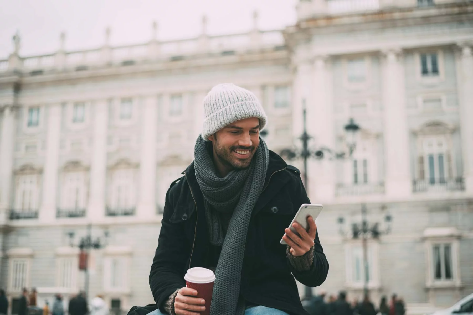 Man looking at phone in front of stone building