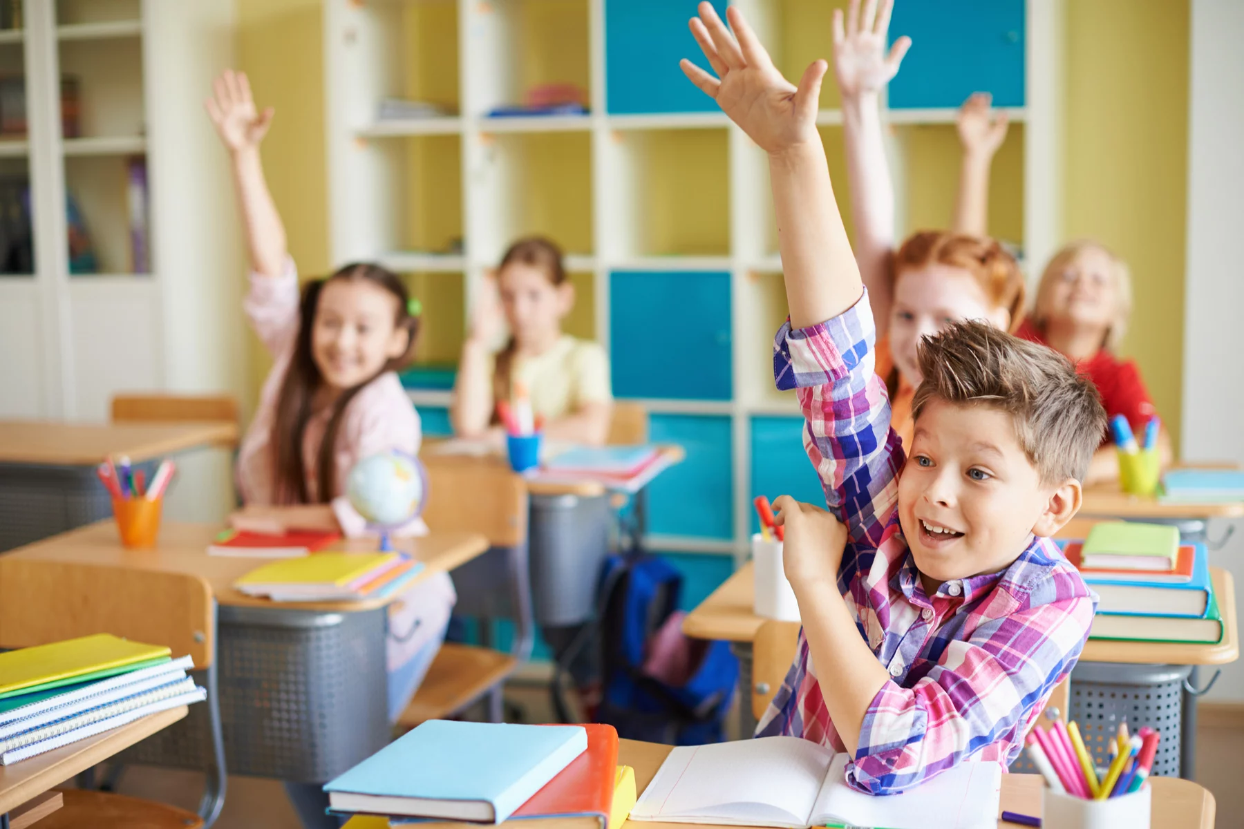 Schoolchildren raising their hands in class