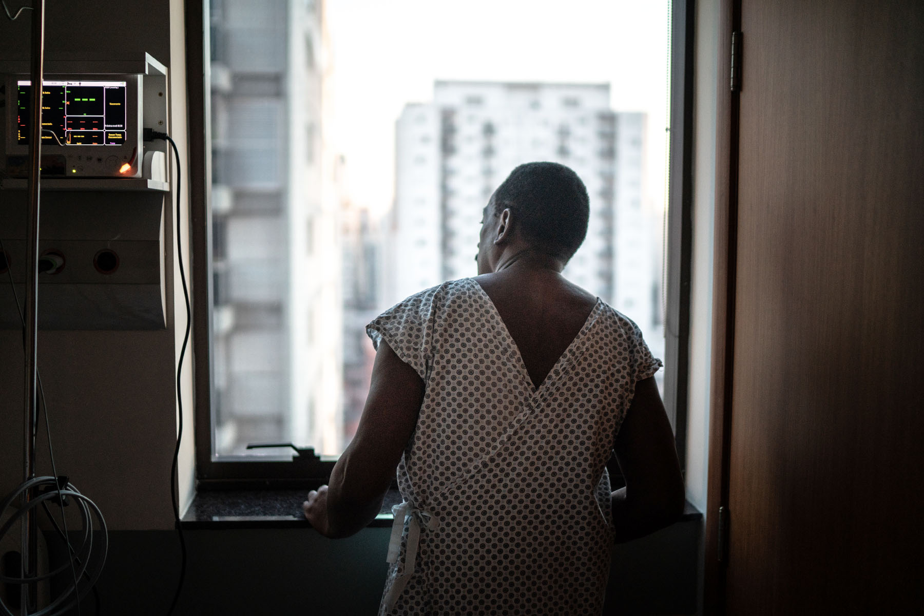 Rear view of a patient at the hospital looking through window.