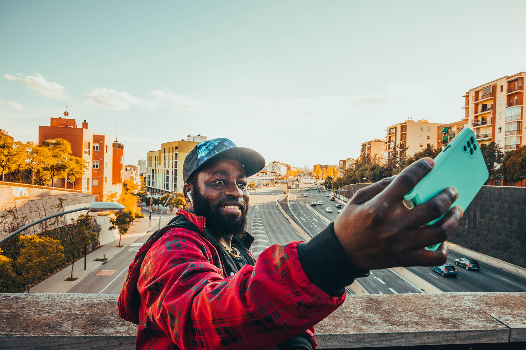 Real people portrait in the streets of Barcelona city, taking selfie picture above the highway with the Barcelona city skyline in the background.