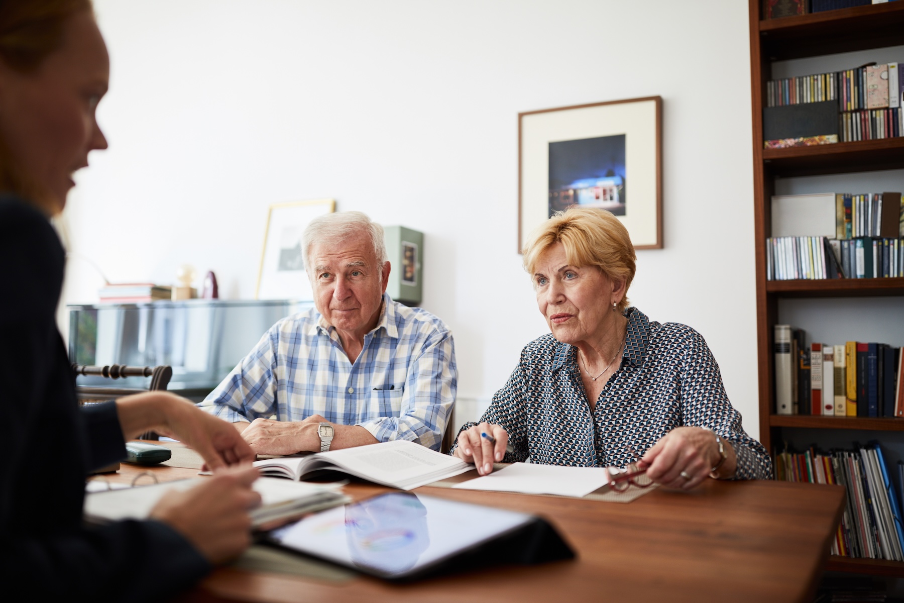 An older couple sits with their financial advisor discussing taxes