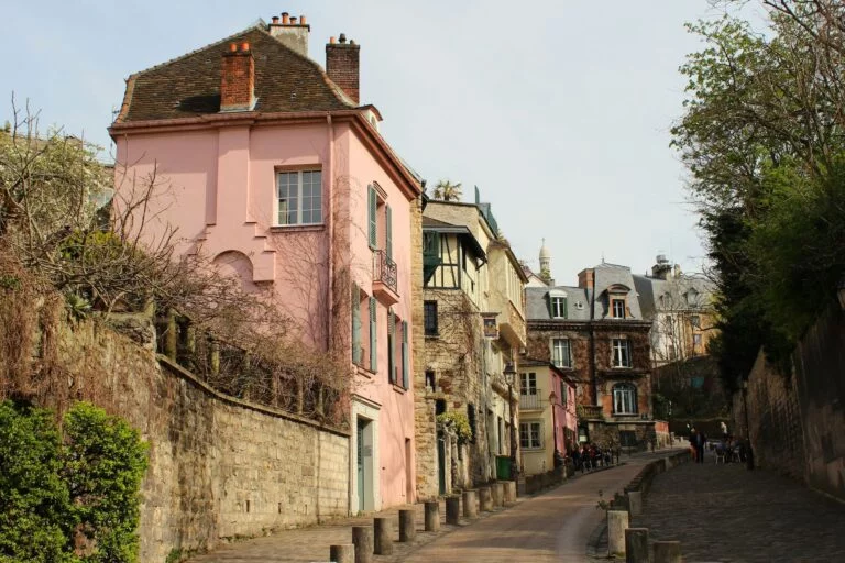A small street in Montmarte, Paris, France with a light pink house on the end