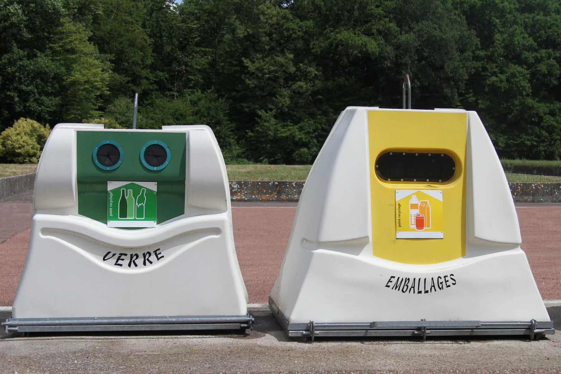 Two unusually shaped recycling bins. They are like malformed triangles. The one on the left has a green label and is for glass. The one on the right has a yellow label and is for packaging.