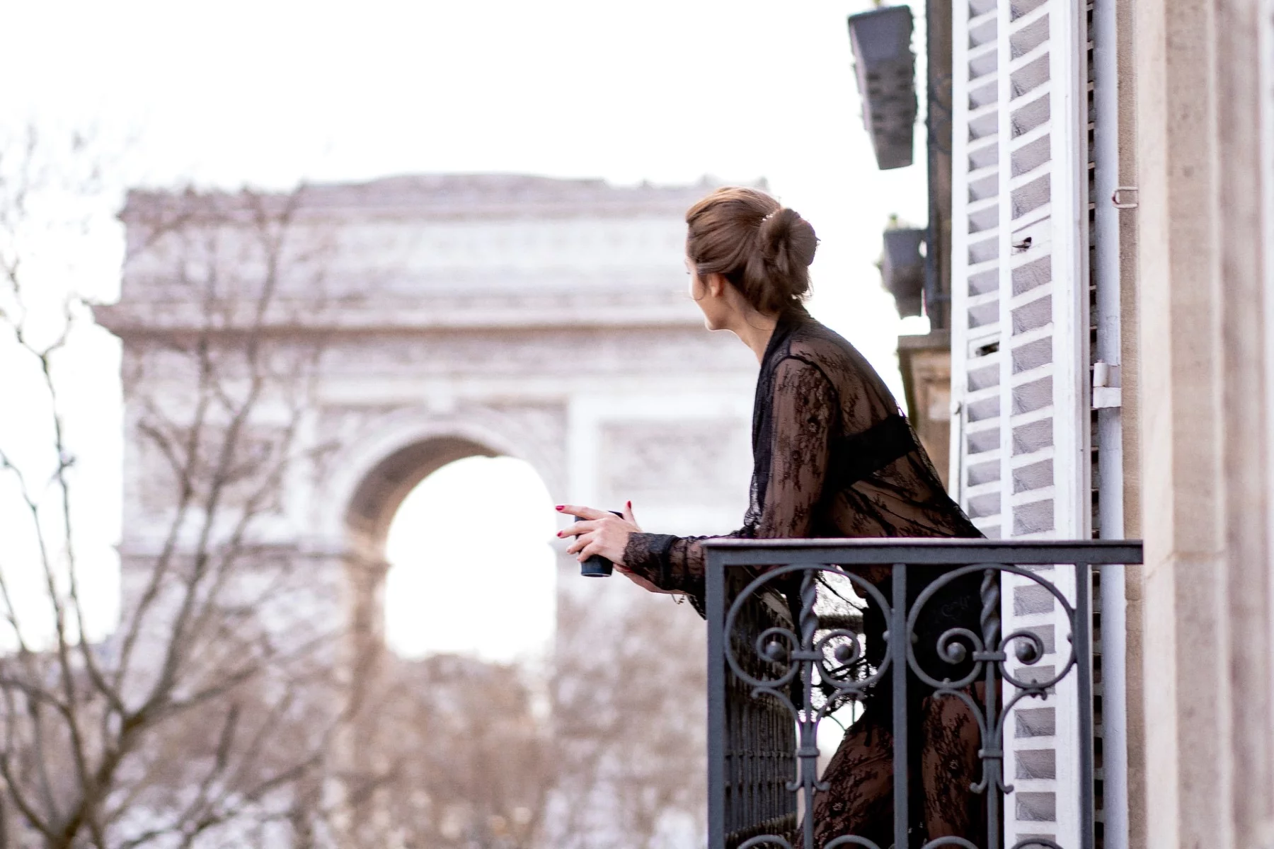 glamorous woman looking out from balcony in Paris.