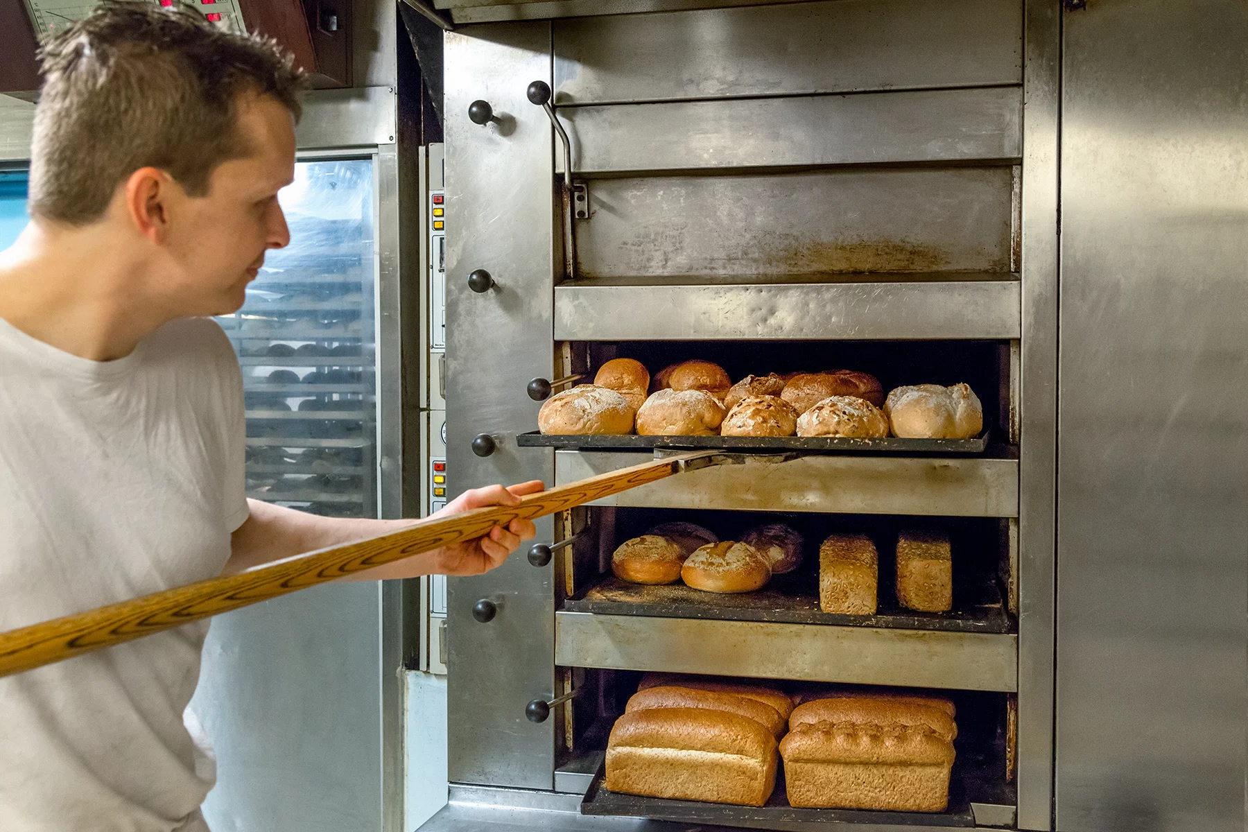 A baker removing bread from the oven