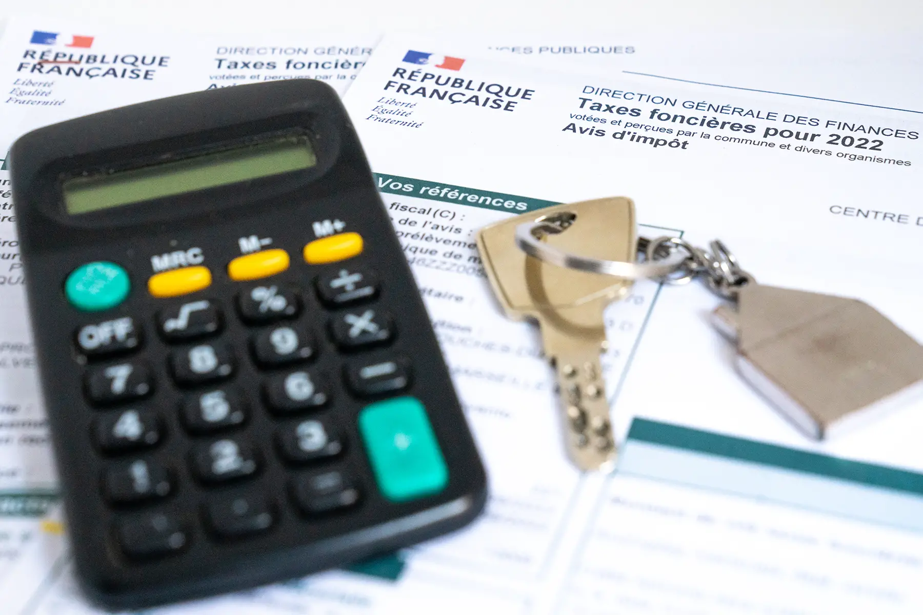 Calculator and house keys lying on top of tax forms