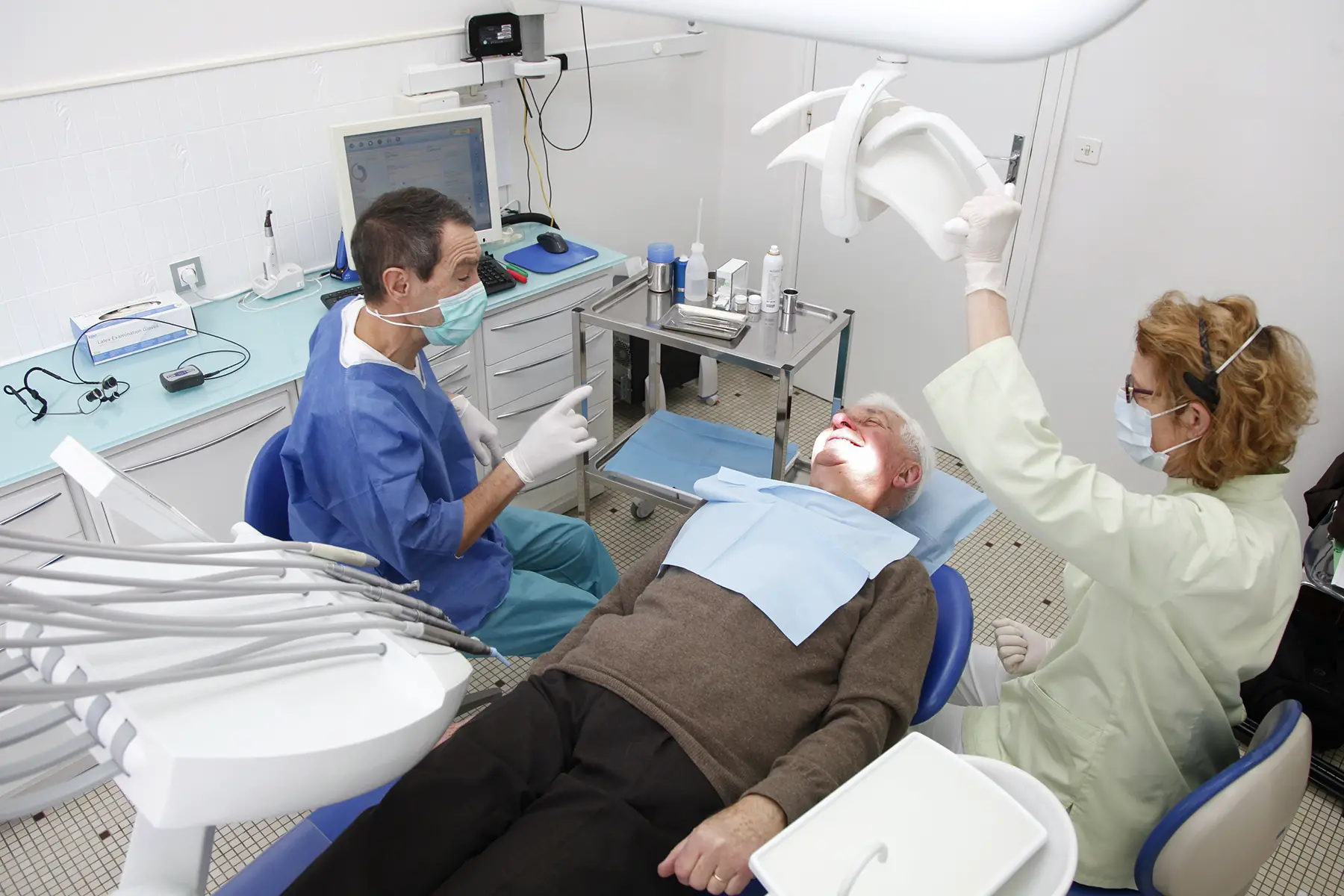 Dentist and assistant working on patient in dentist chair