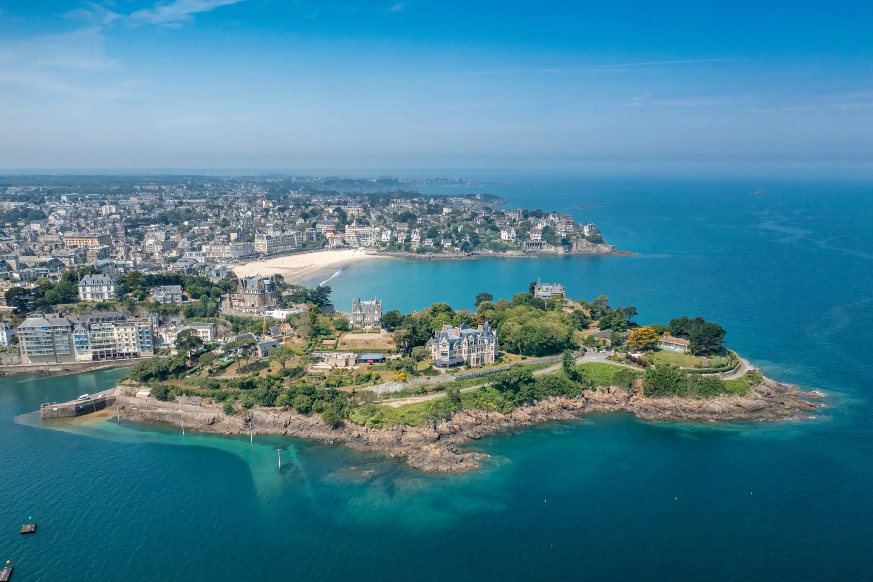 An aerial view of Dinard on a clear sunny day with the bright blue sea surrounding the rocky coastline