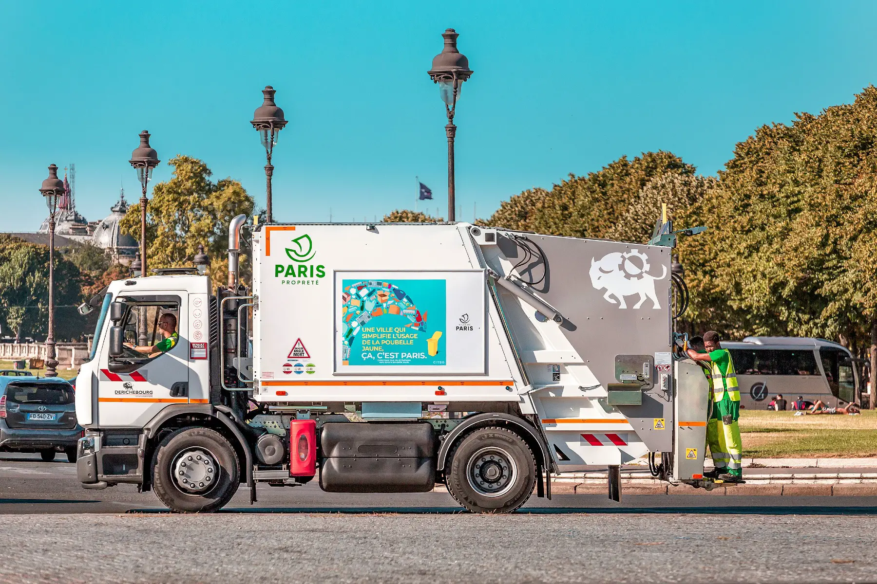 A garbage truck driving through Paris on a sunny day