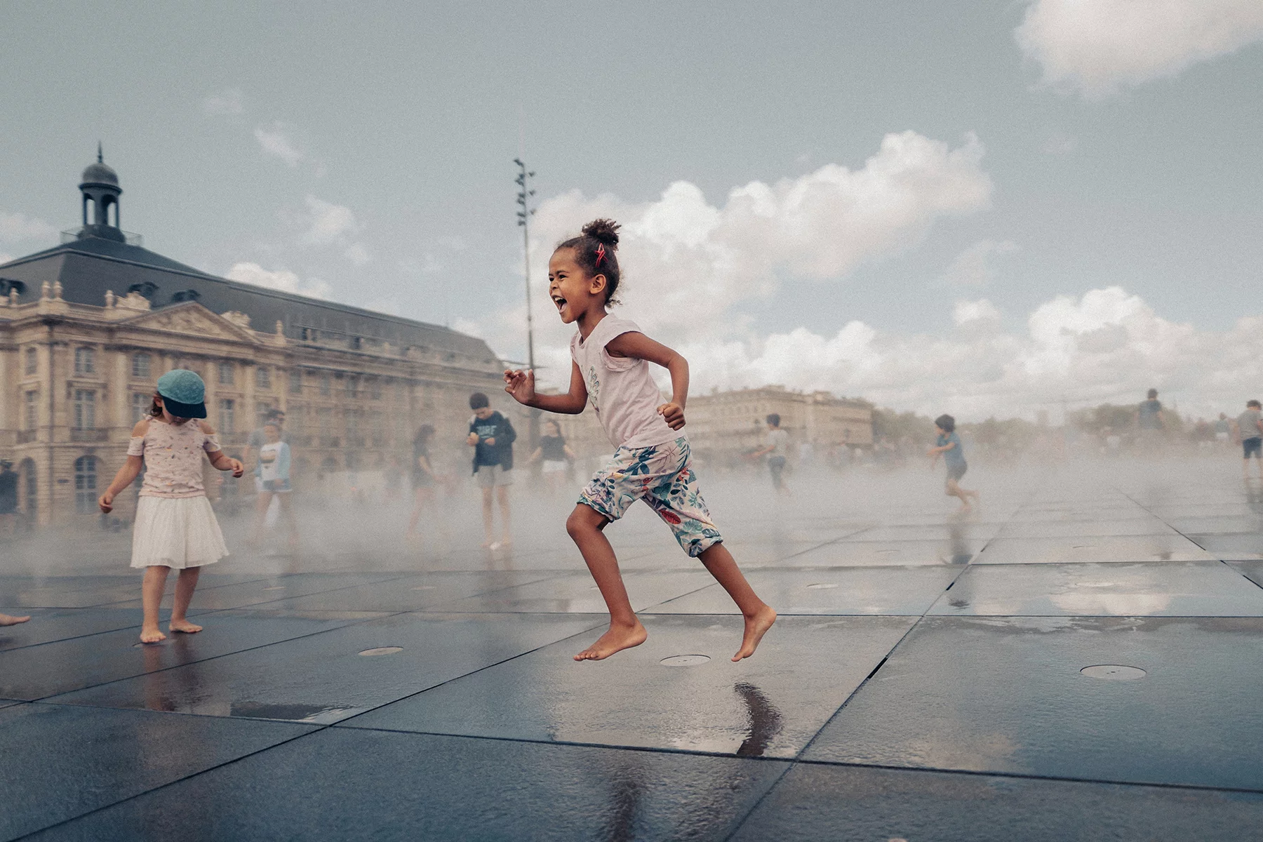 A little girl runs through fountain in Bordeaux, France 