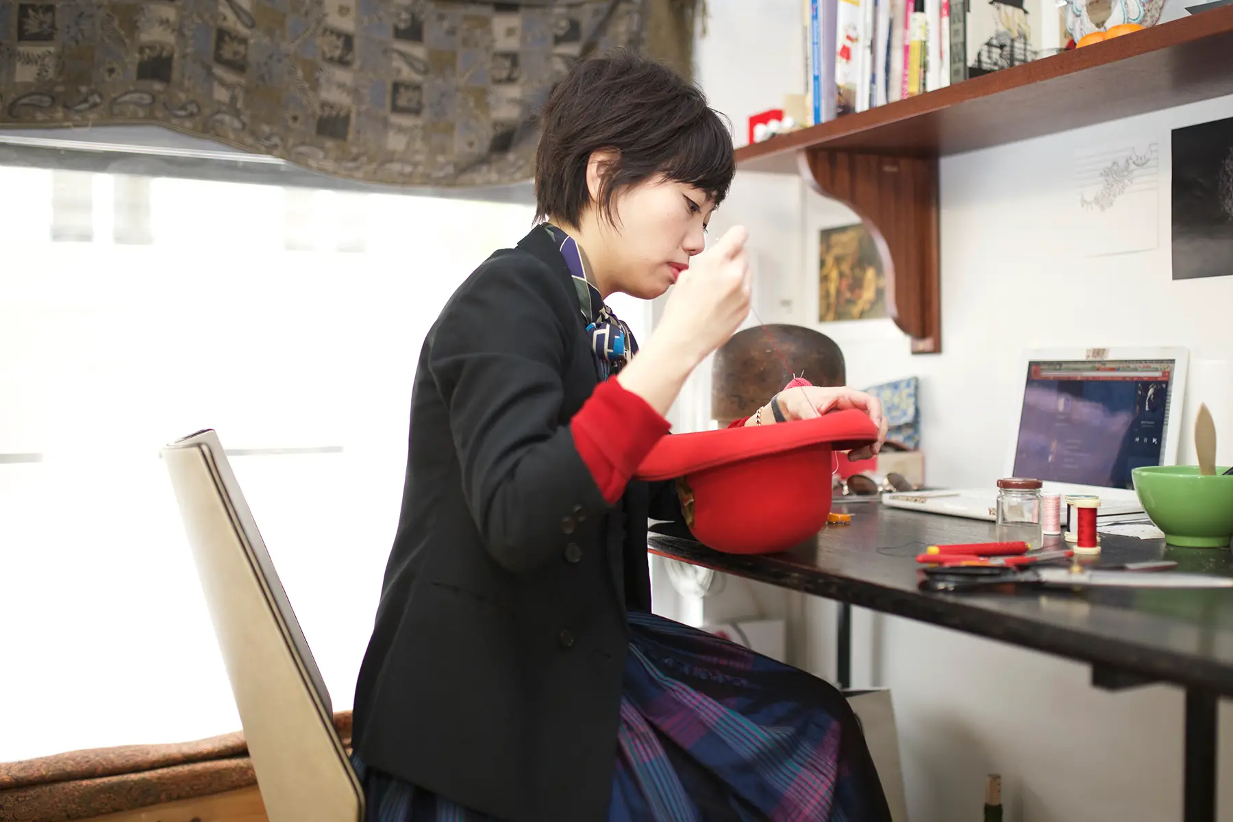 A woman making a hat at a desk