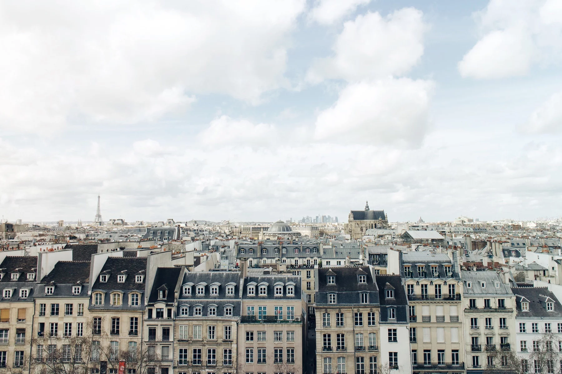 Bird's eye view of typical Parisian Haussmann roofs, with the Eiffel Tower in the background. Photo by Nil Castellvi