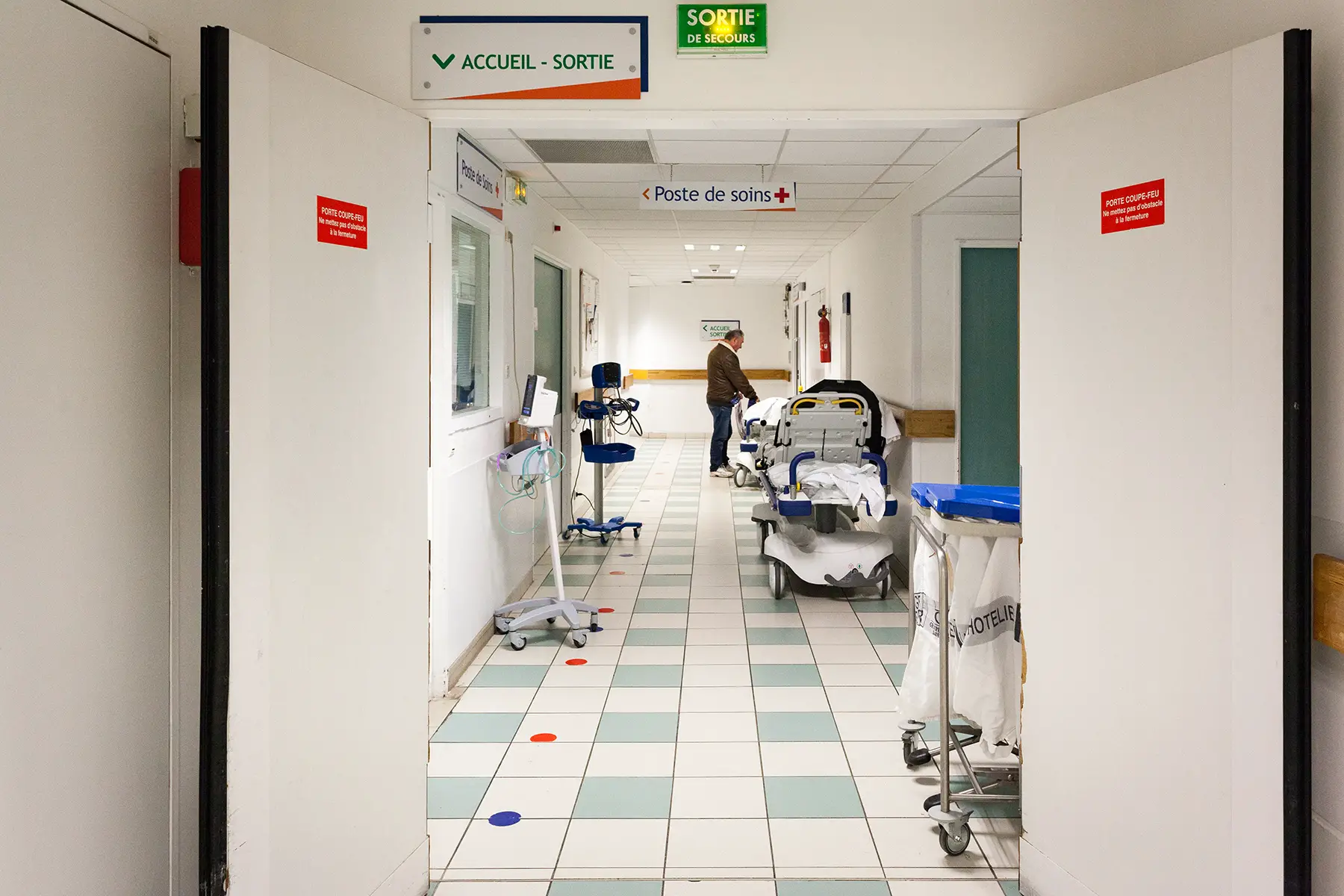 A man stands at the end of a long, empty hospital corridor in Aix-en-Provence, France