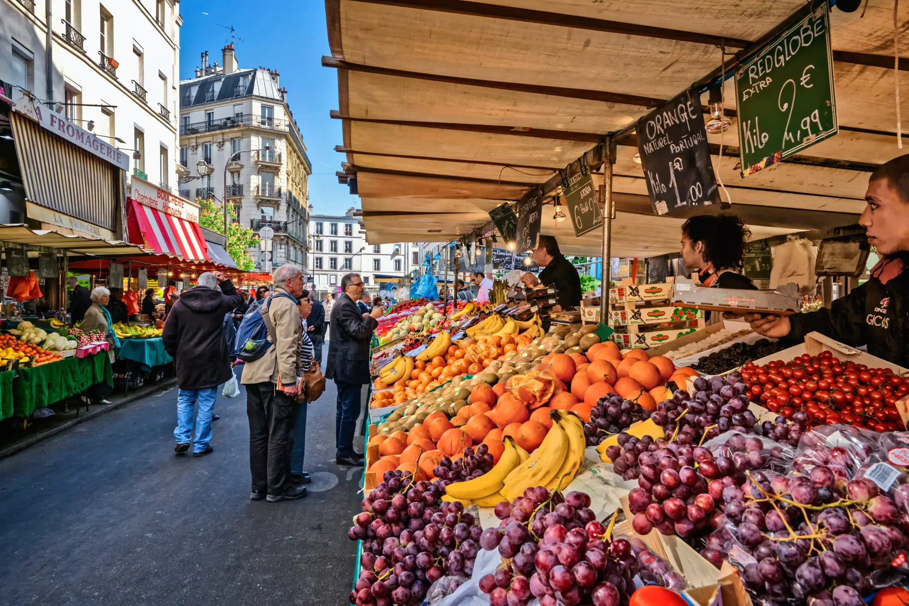 Customers speaking to fruit seller at the Aligre Street Market in Paris