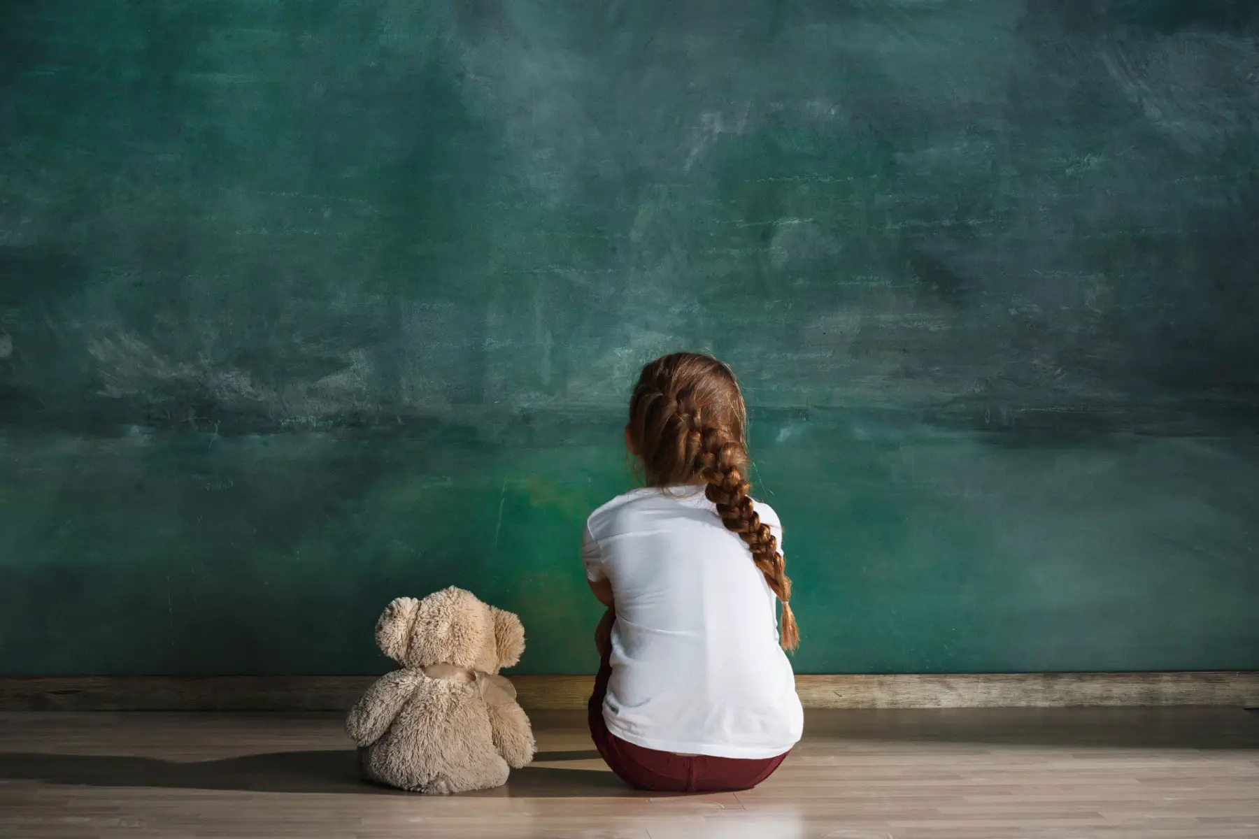 young girl staring at blackboard with soft toy