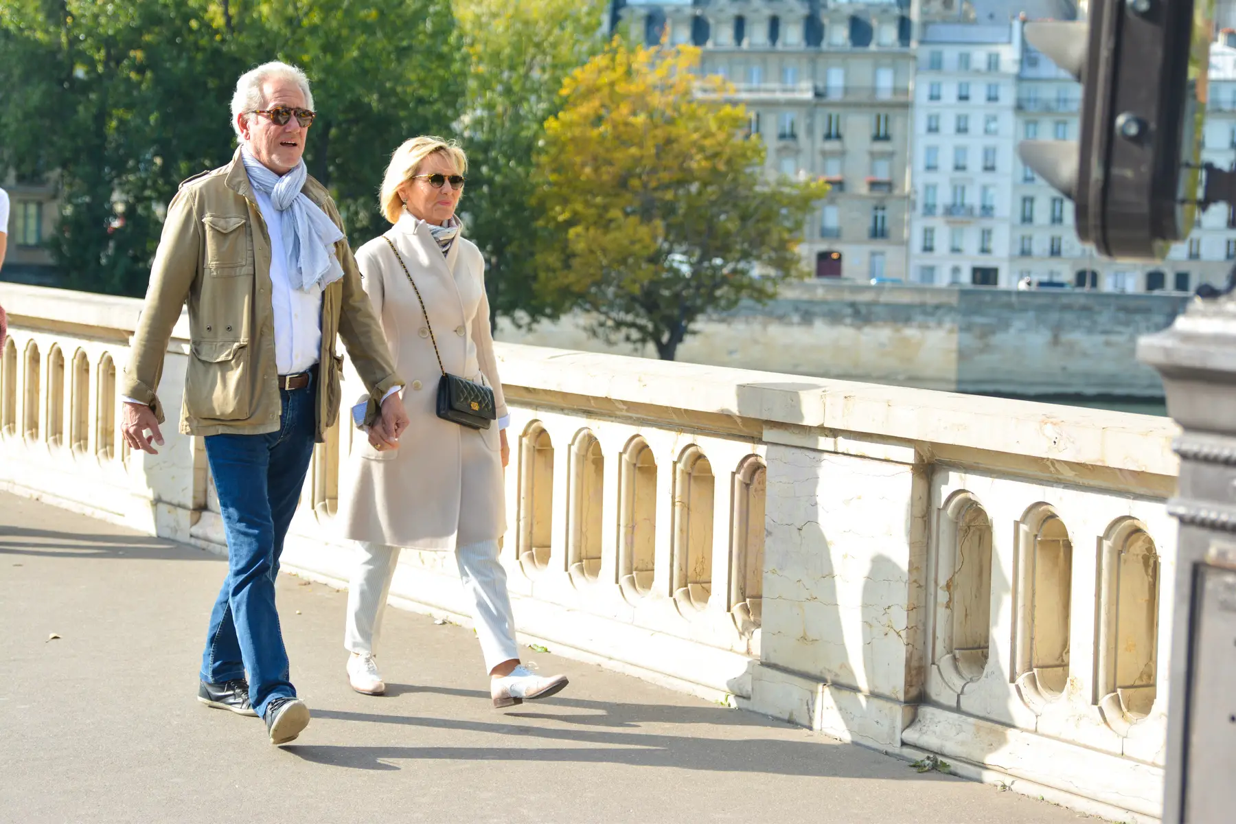 French pensioner couple walking hand-in-hand on a bridge in Paris