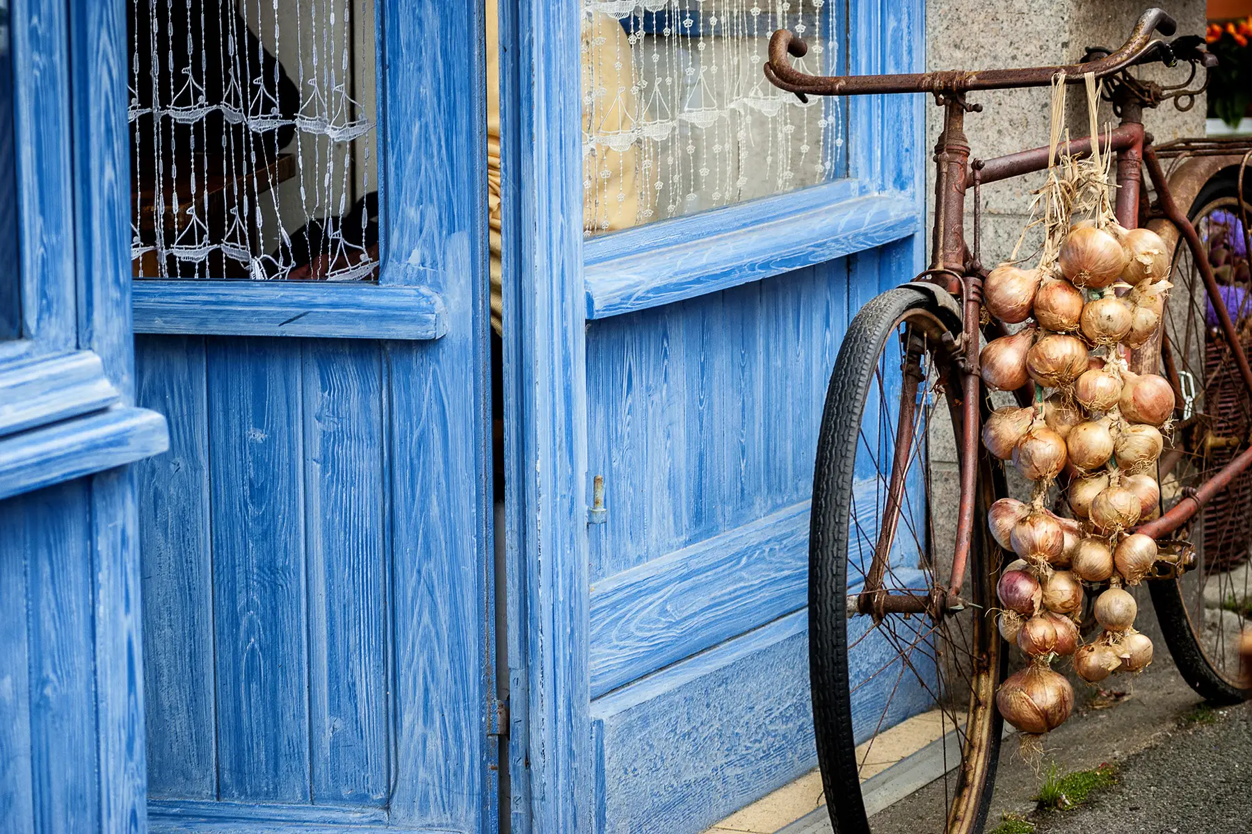 Onions hang from a bicycle outside a French home or shop