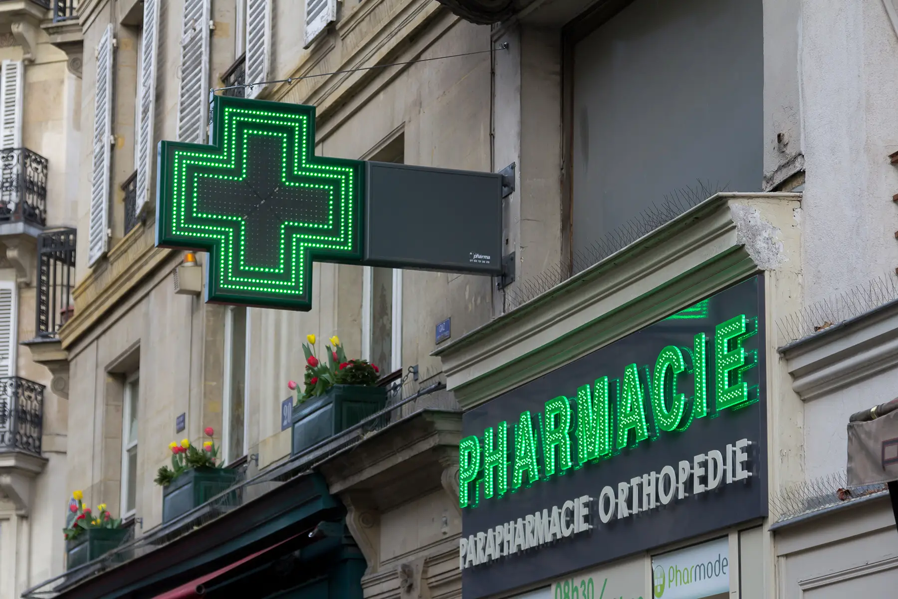 A pharmacy in Paris, France with a neon green sign above it