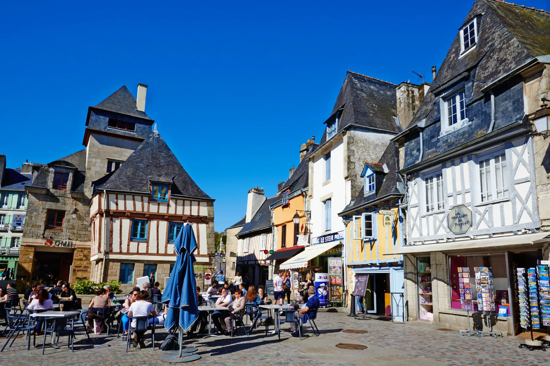 a busy square in the historic center of Quimper with people sitting and drinking on a terrace surrounded by old timber-framed houses