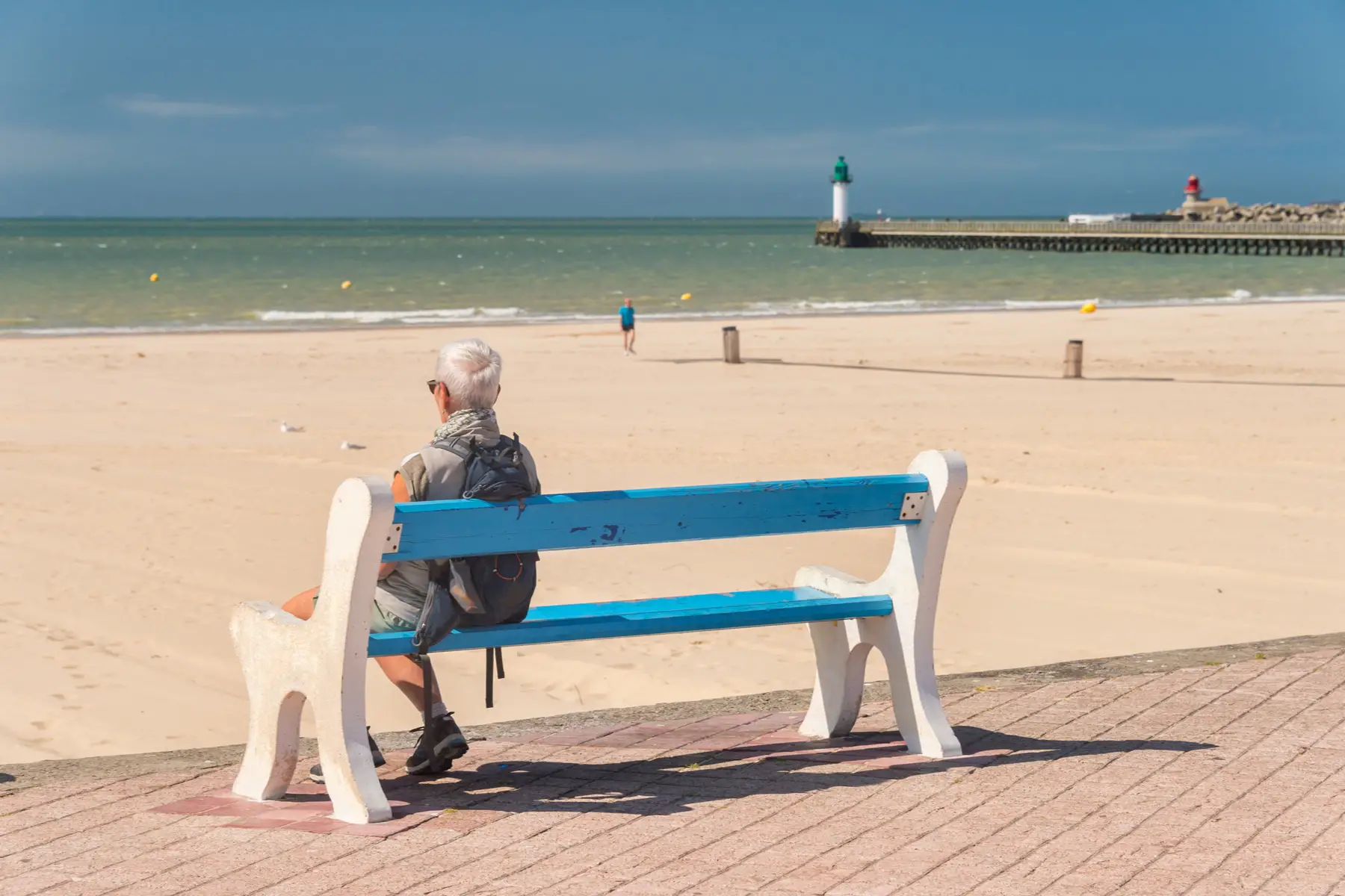 a retiree in France on a bench at the beach
