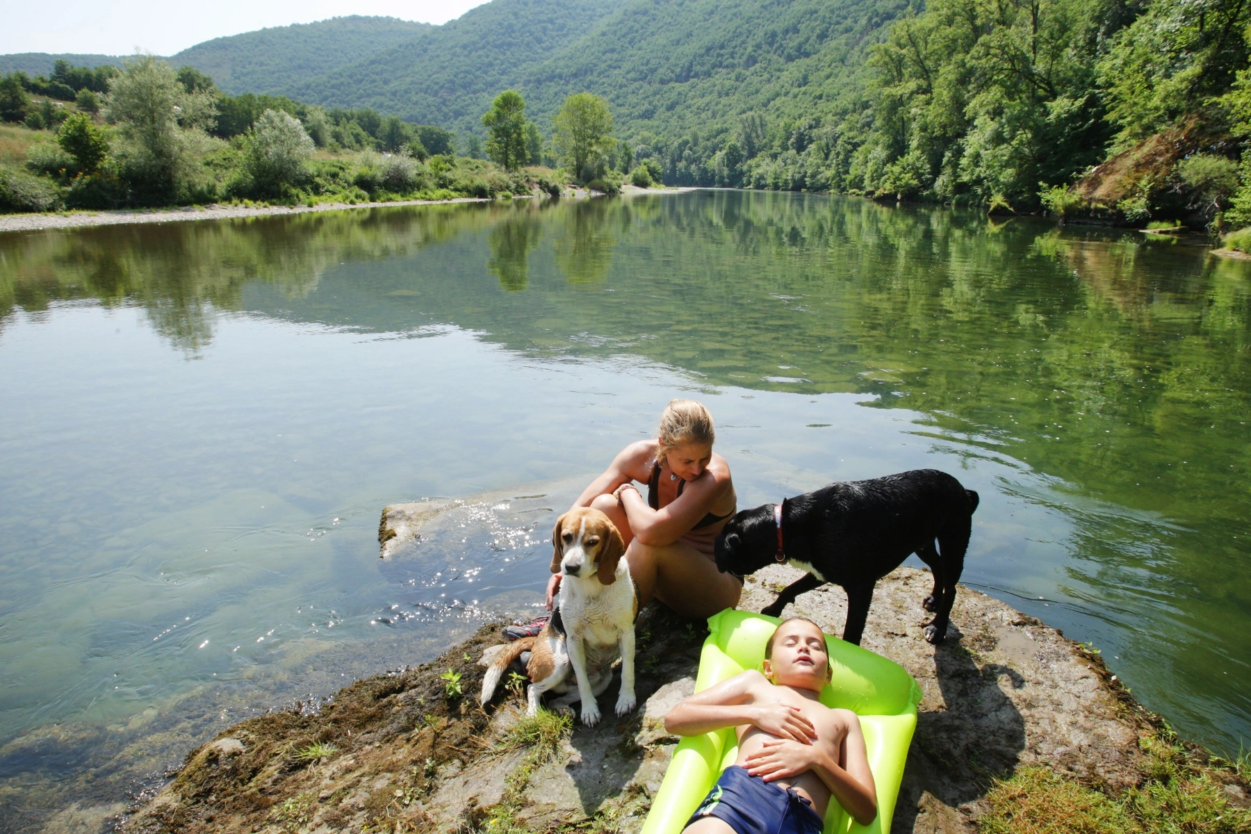Mother and child relaxing with two dogs at Tarn river in the south of France