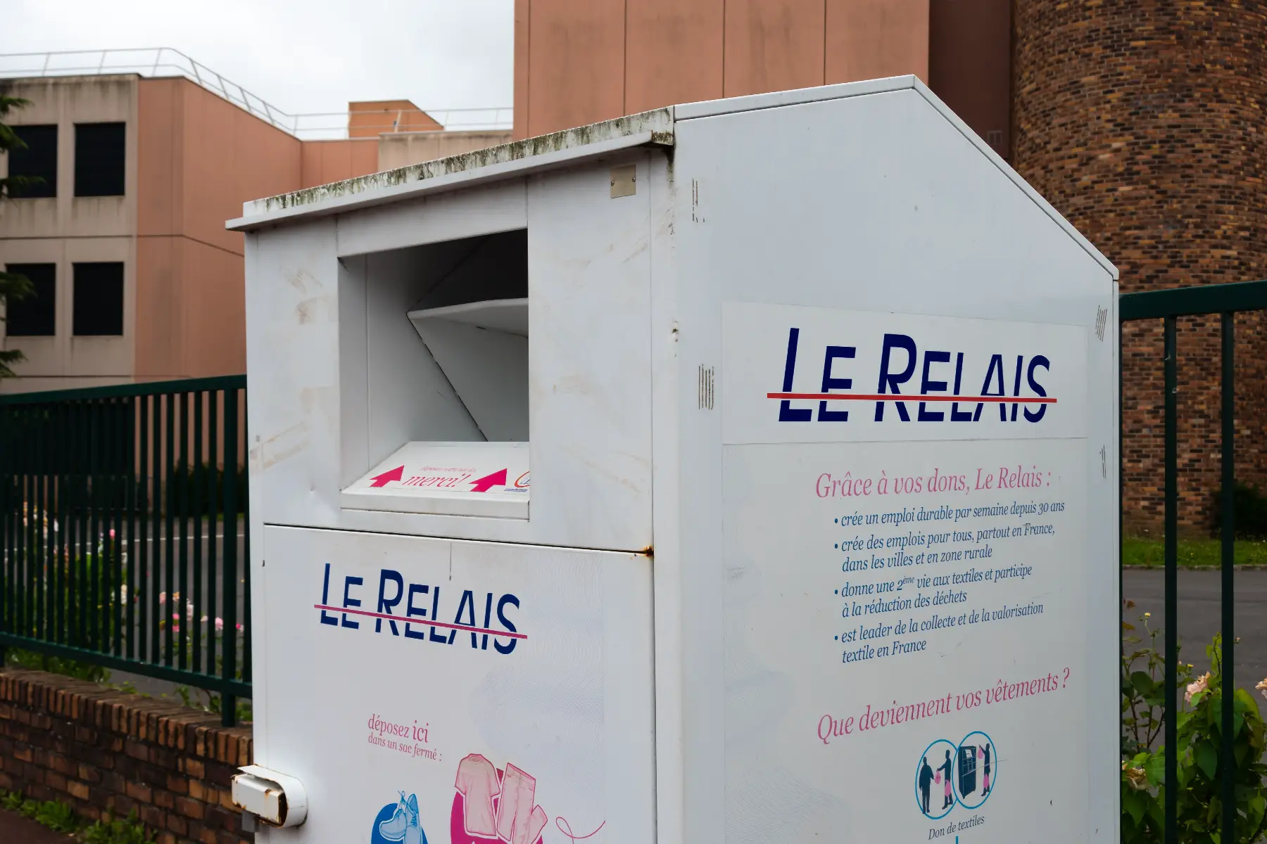 Textile recycling bin for social enterprise Le Relais. It is grey, about two meters tall and shaped like a shed.