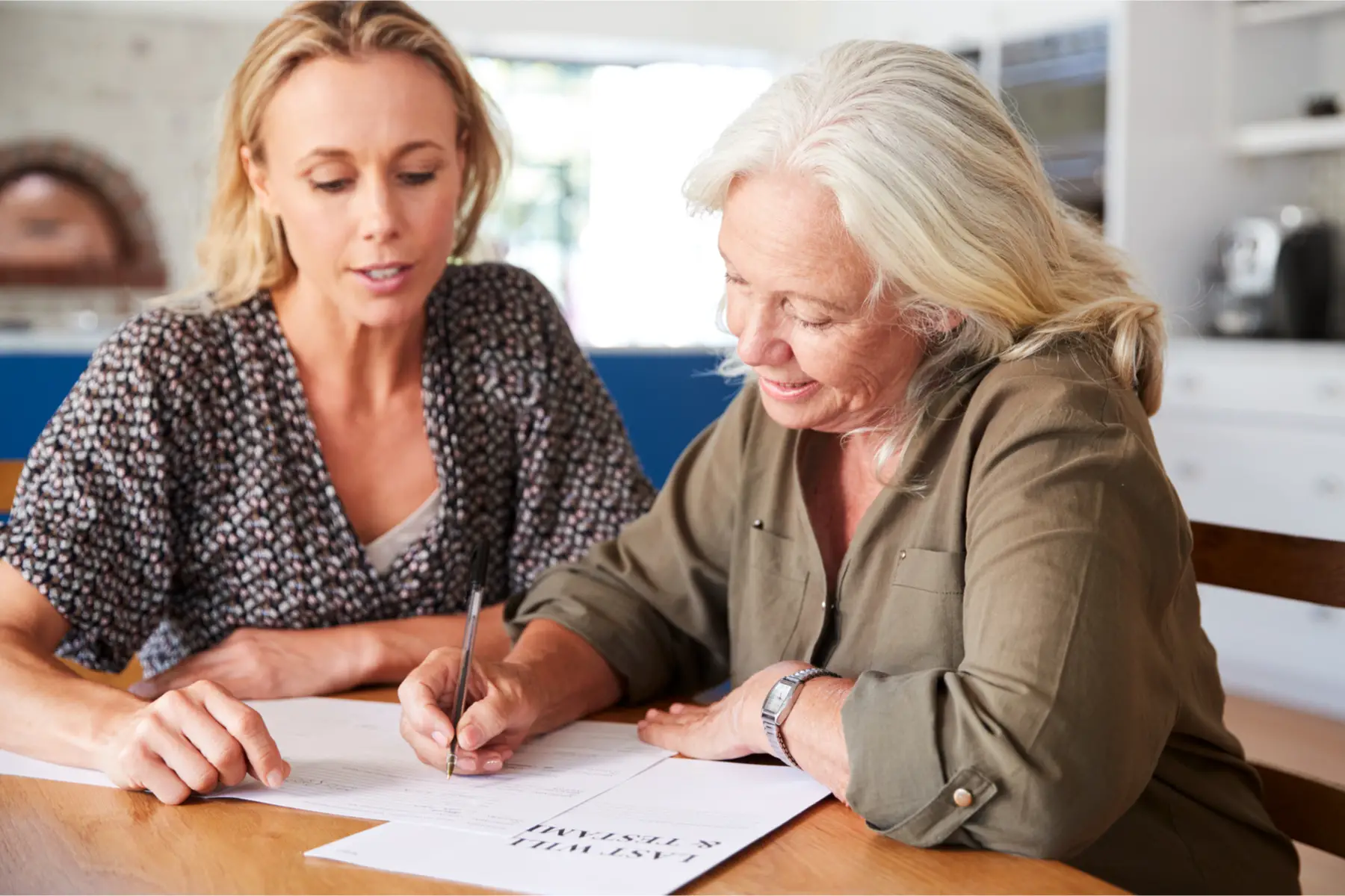 a young woman witnesses an older woman signing her will
