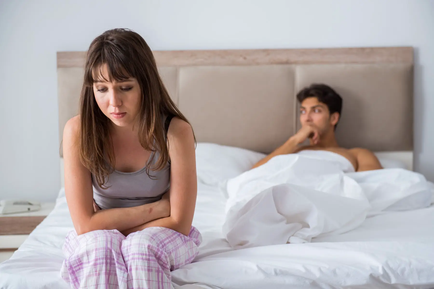 unhappy, distant couple in bed