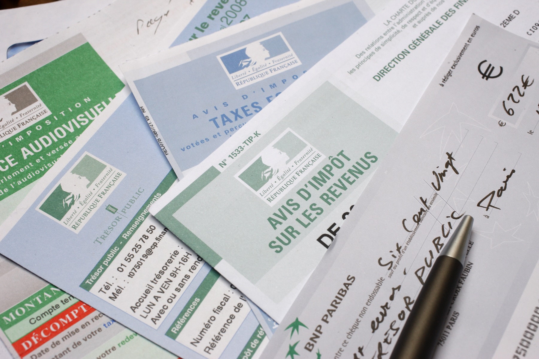 Several French income tax forms are stacked on top of each other, including a check