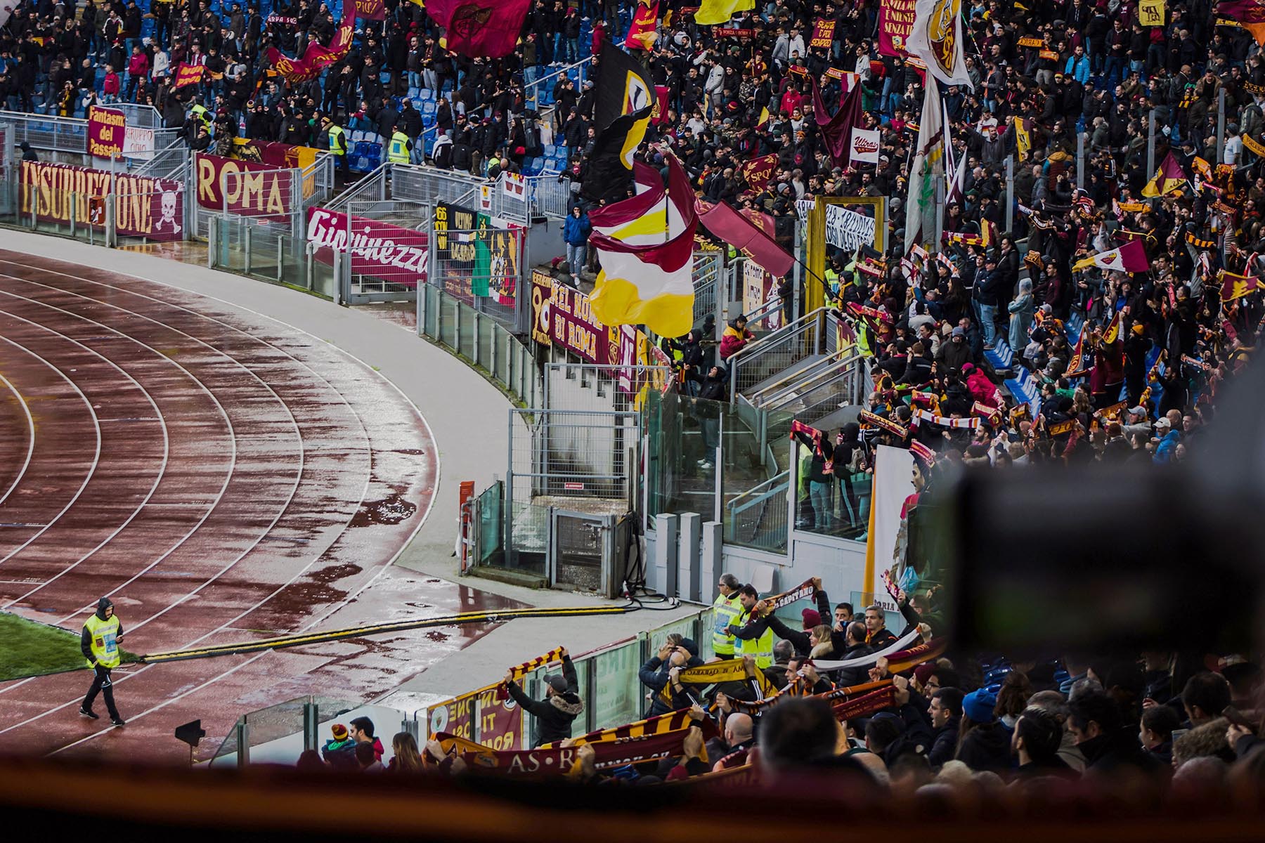 Large crowd of AC Roma supporters standing in the stands of a stadium.