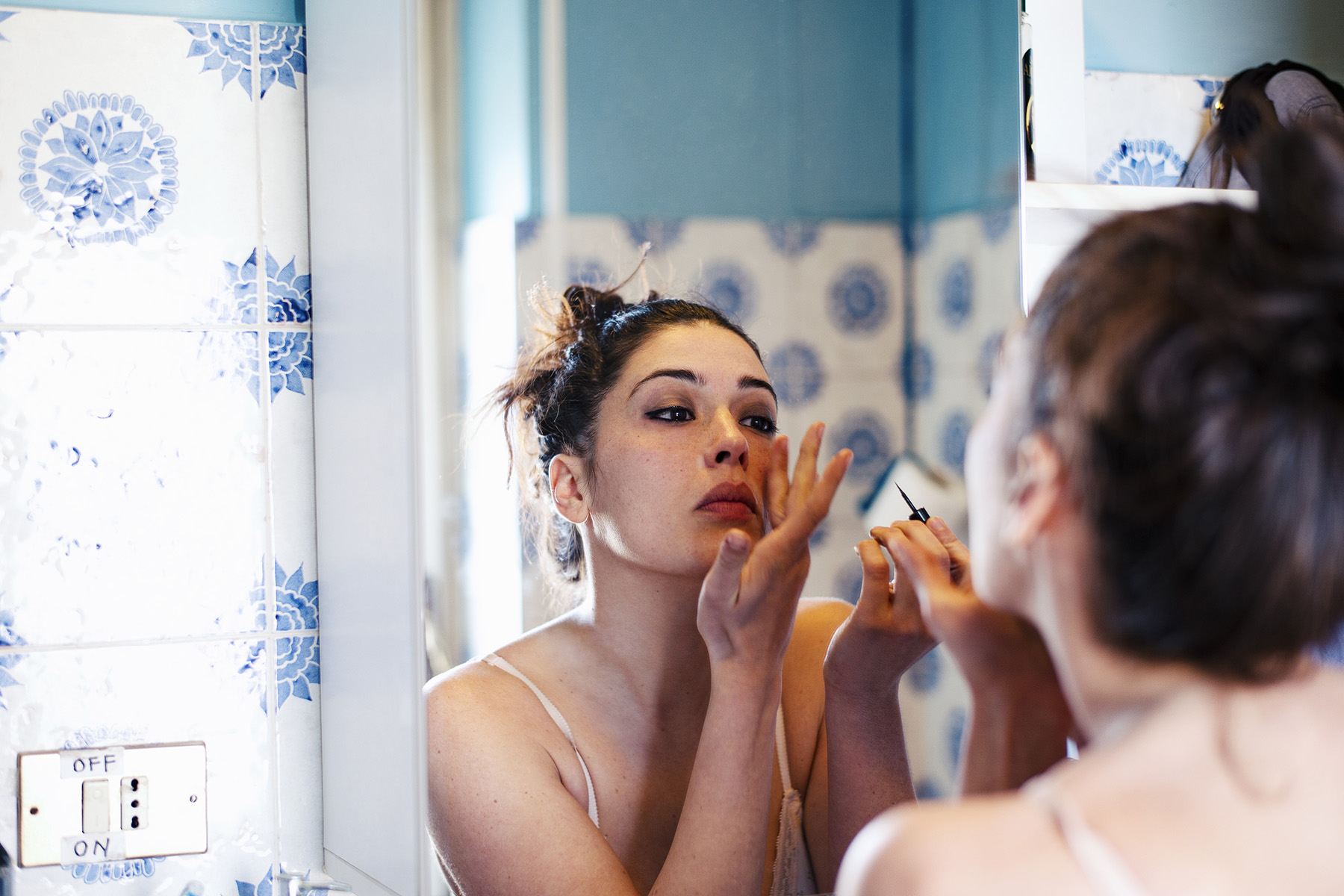 Woman in front of a mirror putting on make-up.