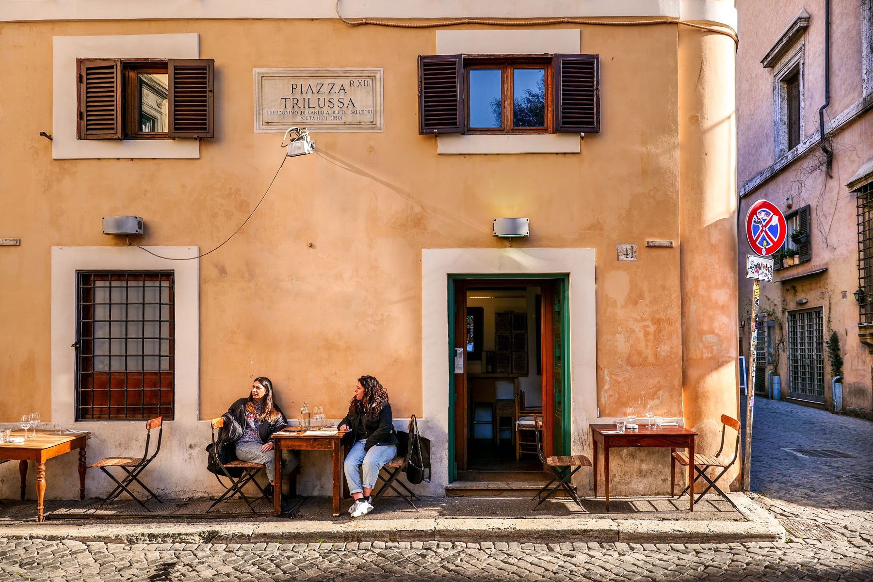 Two women sitting outside a bar in the ancient Trastevere district of Rome.