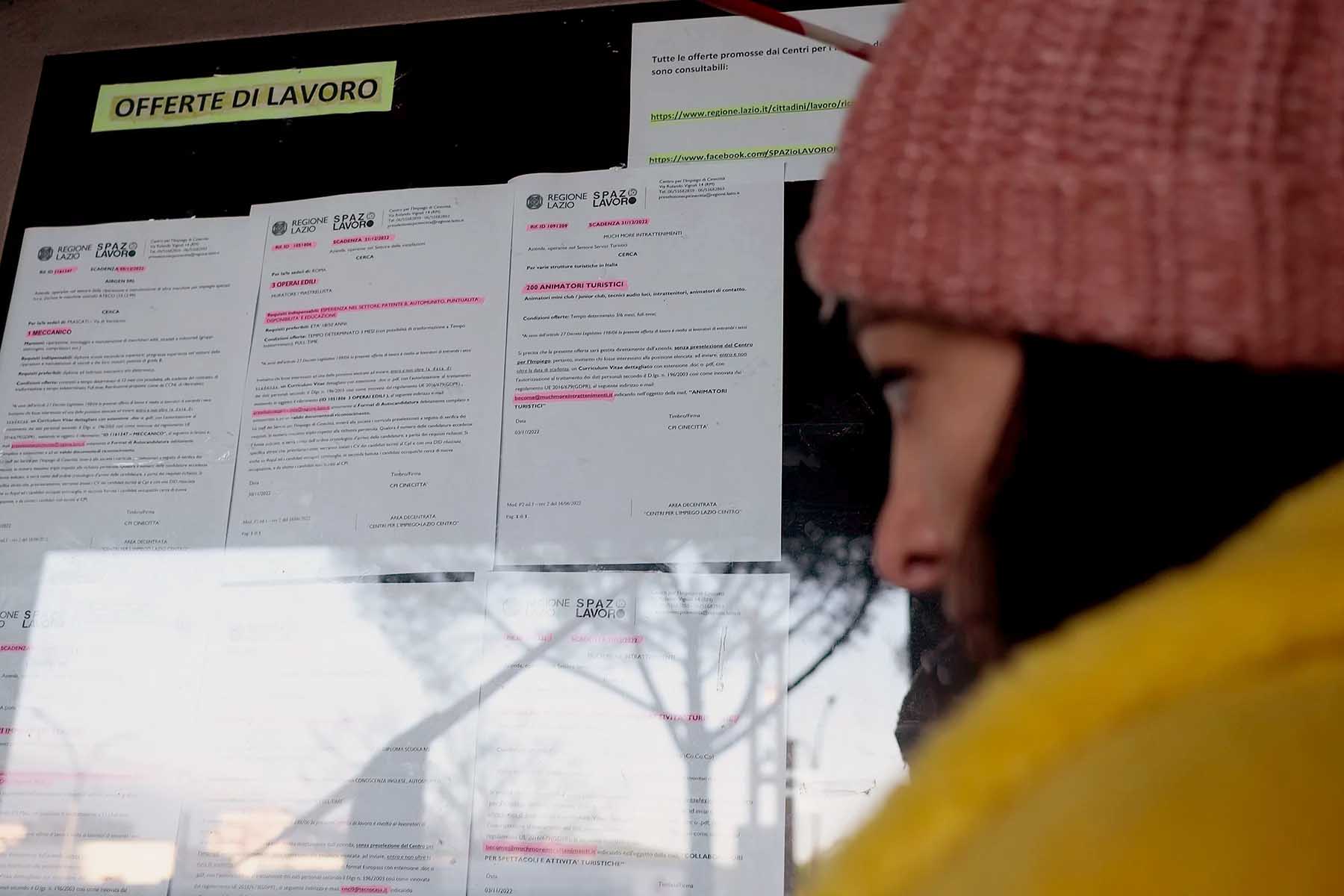 A woman browsing a job board outside a job center in Italy.