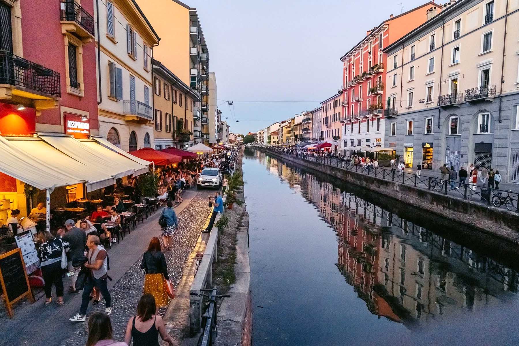 People walking by a canal during the early evening in Navigli, Milan